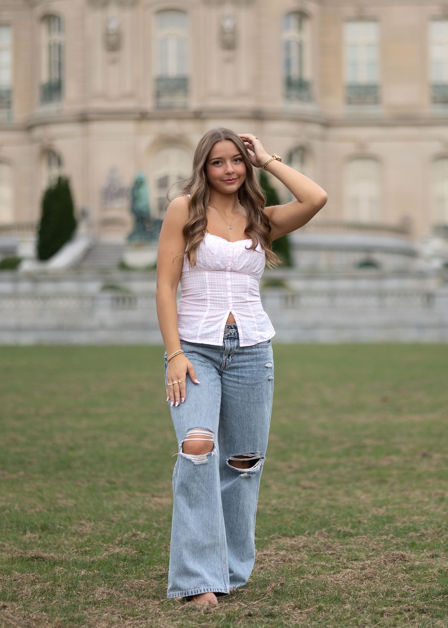 Casual fashion photos on grass featuring ripped jeans and a white top against a stone building backdrop.
