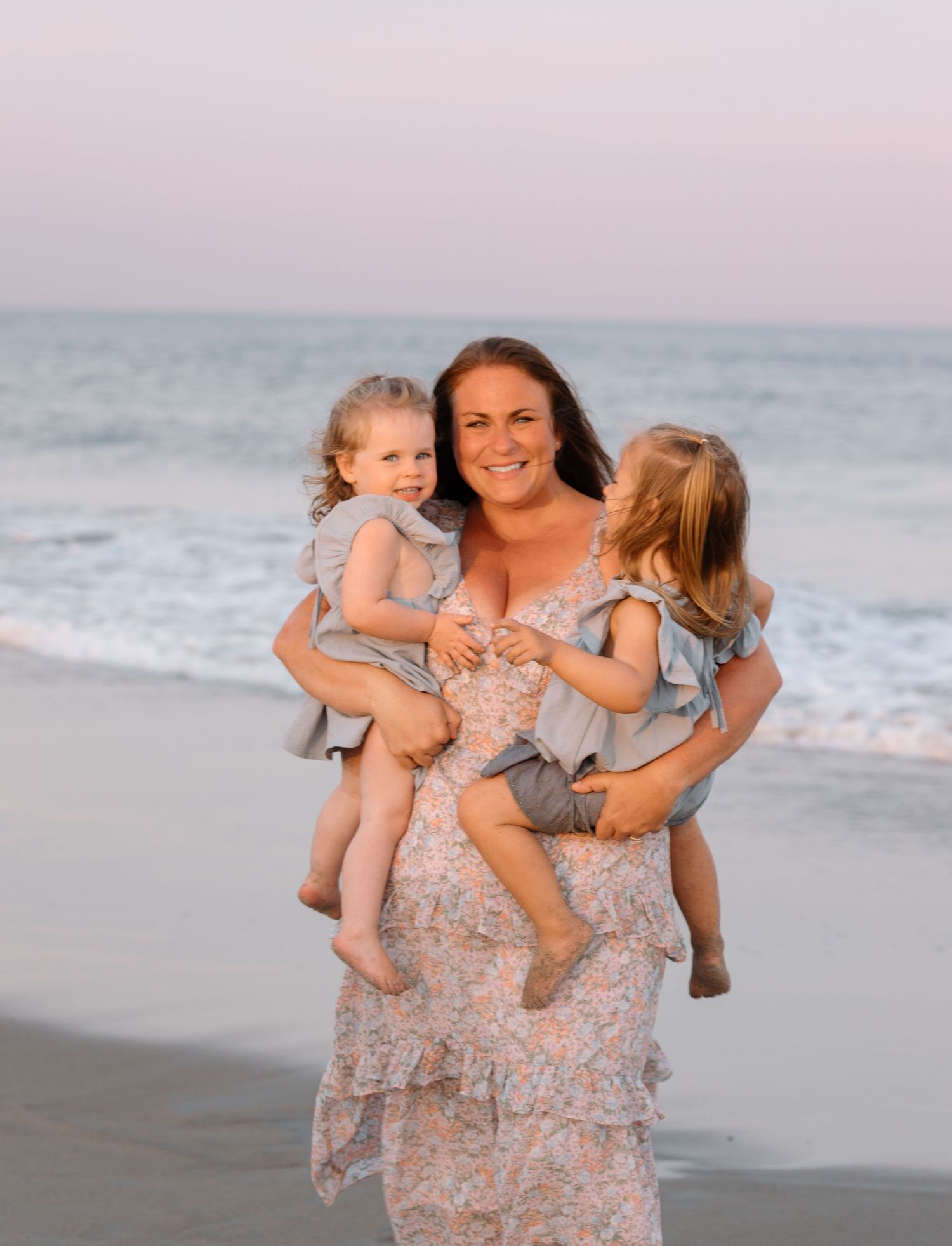 A tender beach portrait with a floral dress against the ocean backdrop.