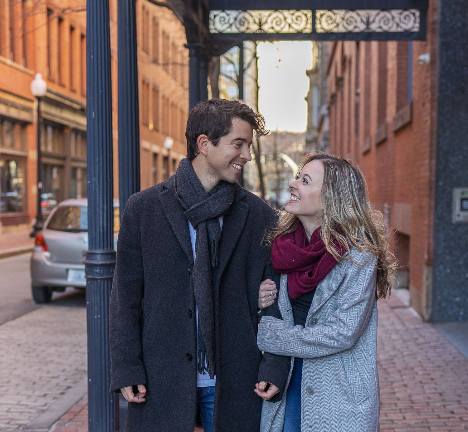 A couple sharing a tender moment under an ornate archway in a historic district.