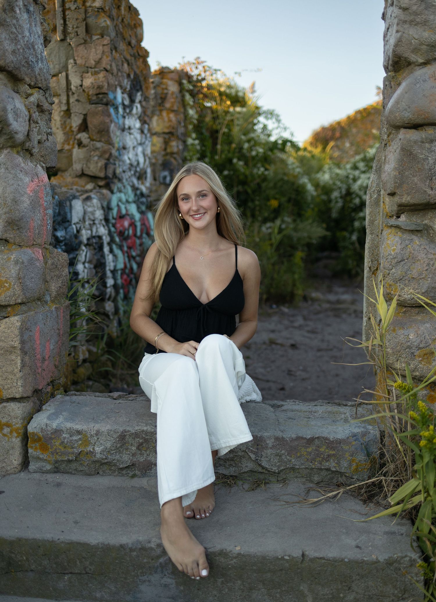 Fashion portrait at stone ruins with graffiti and natural greenery.