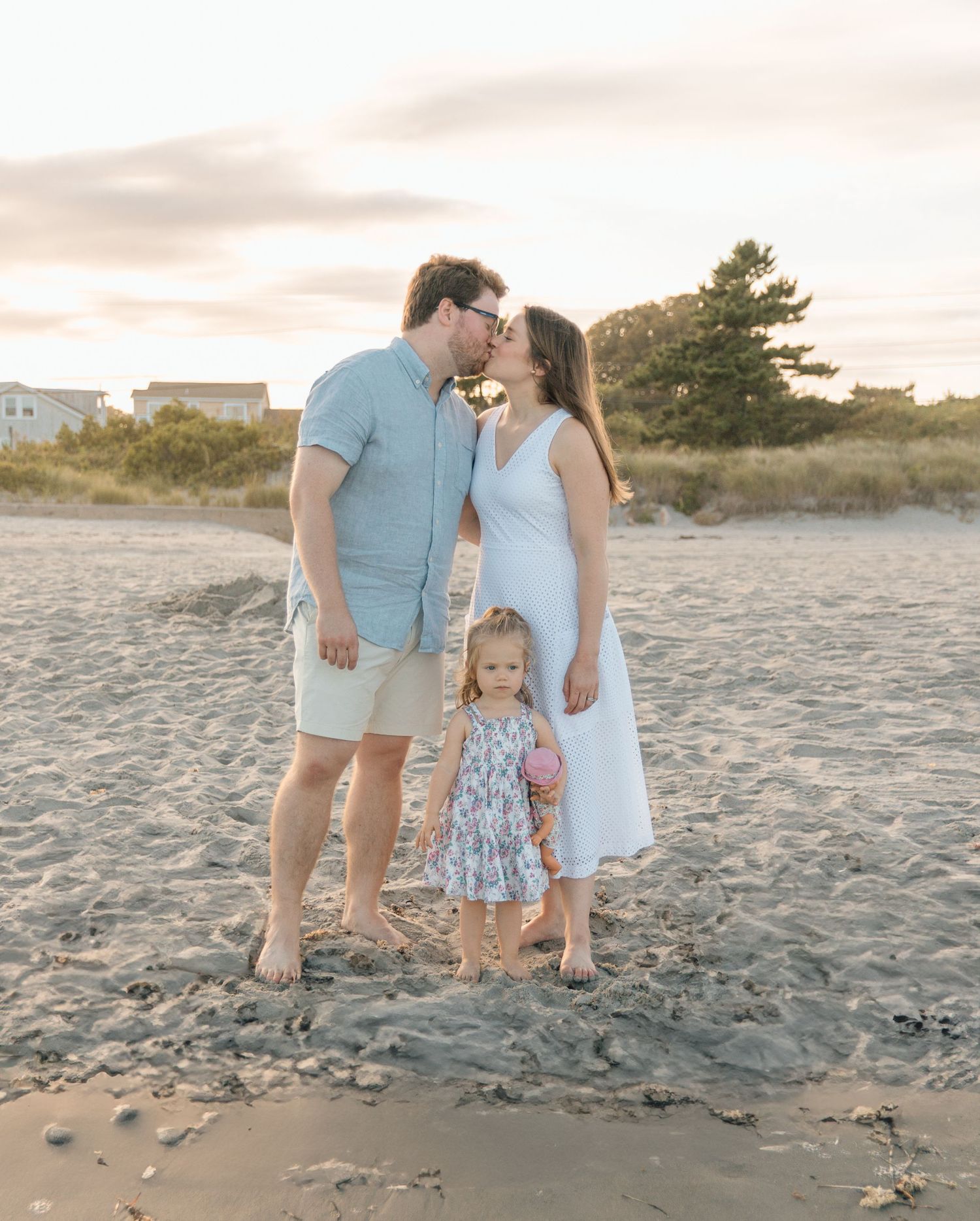 A family shares an intimate moment together on the beach at sunset.