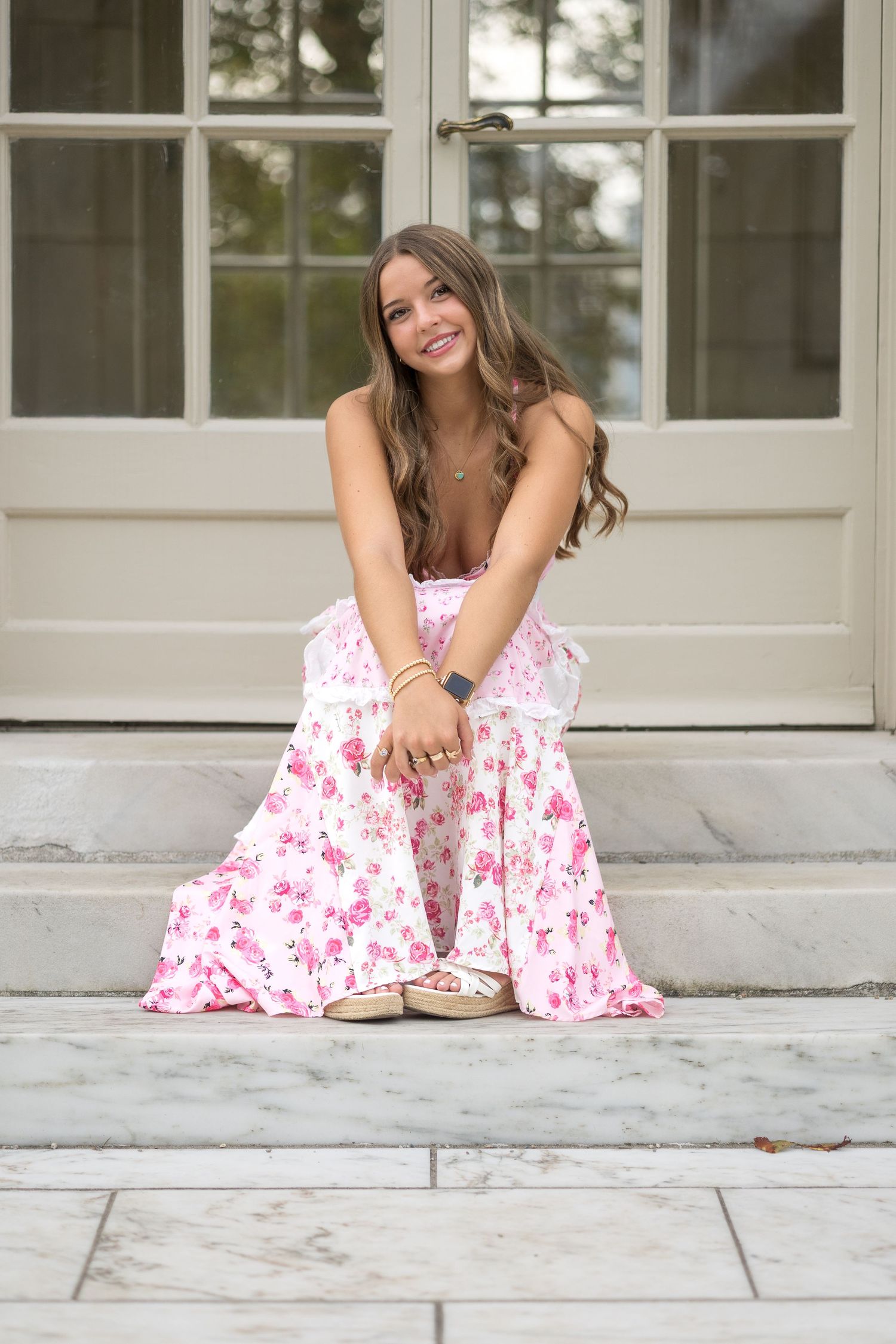 Portrait series on stone steps showing a flowing pink floral dress in different seated poses.
