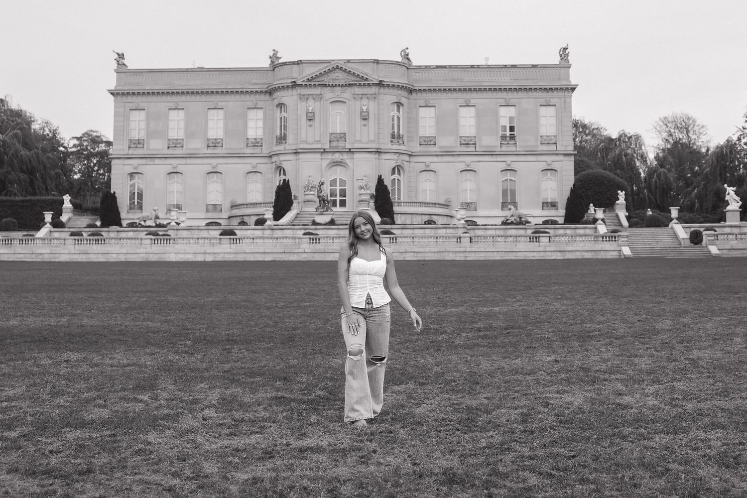 Wide landscape view of a grand historic mansion with expansive lawn in black and white.
