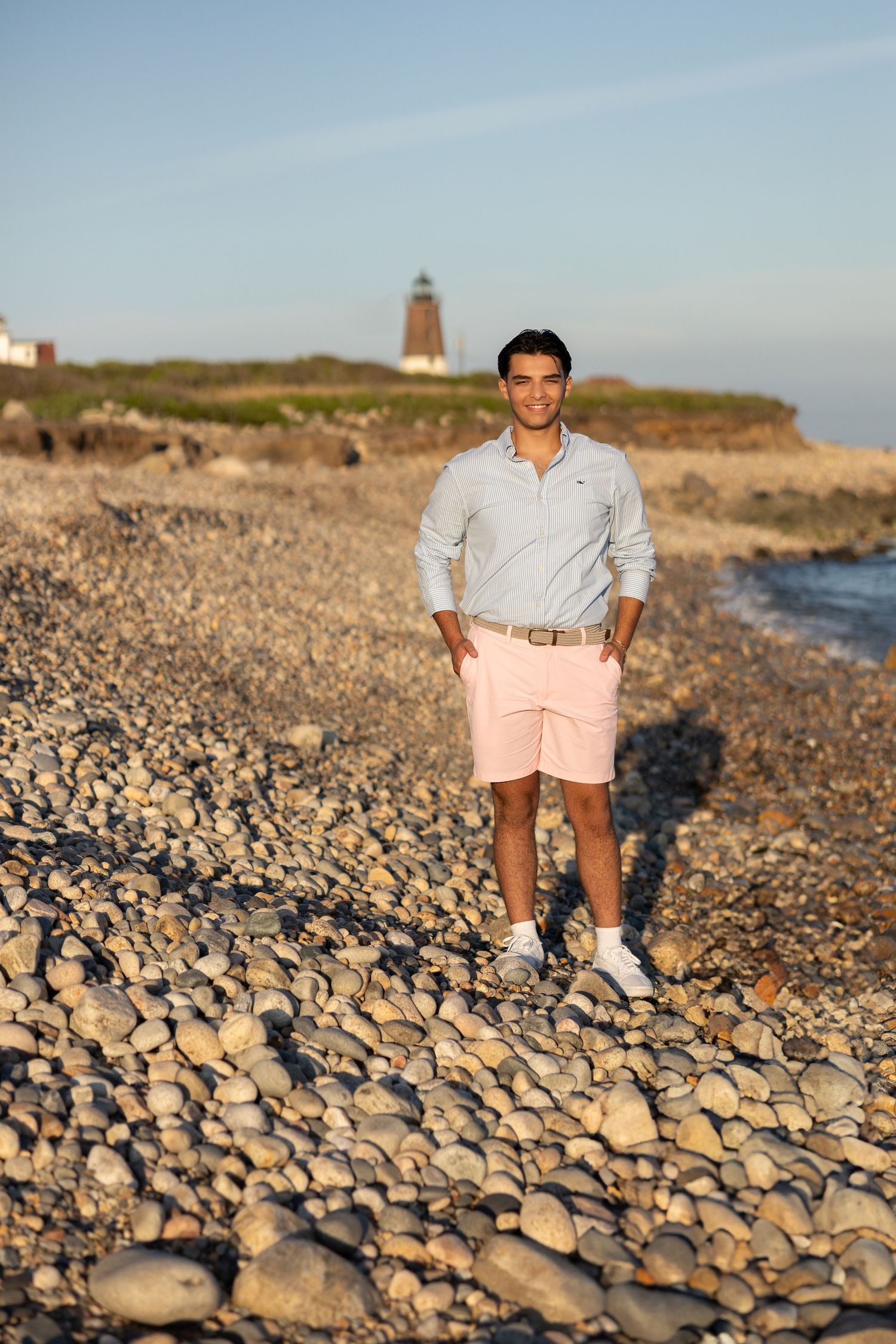 A rocky beach landscape with a lighthouse and coastal scenery at sunset.
