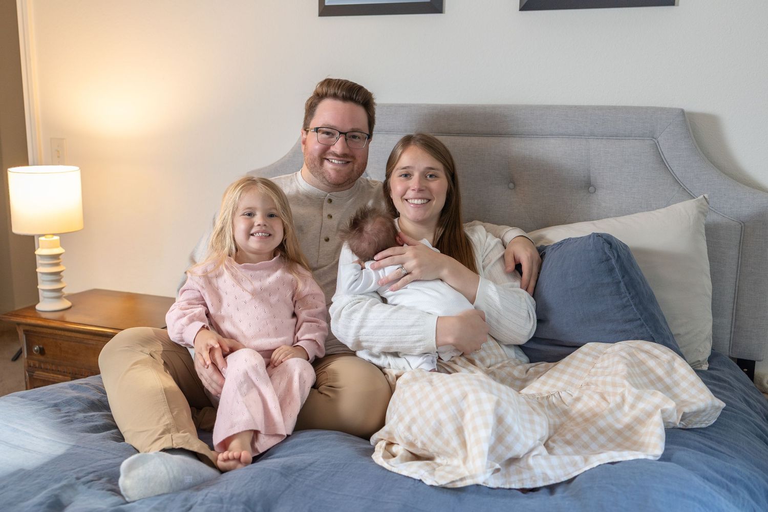 Family members relax together on a gray couch in a cozy living room setting.
