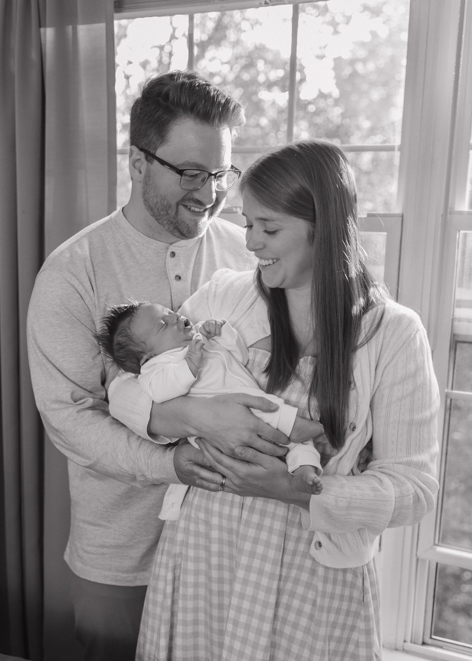 Intimate family moment in a sunlit room with white and neutral tones.
