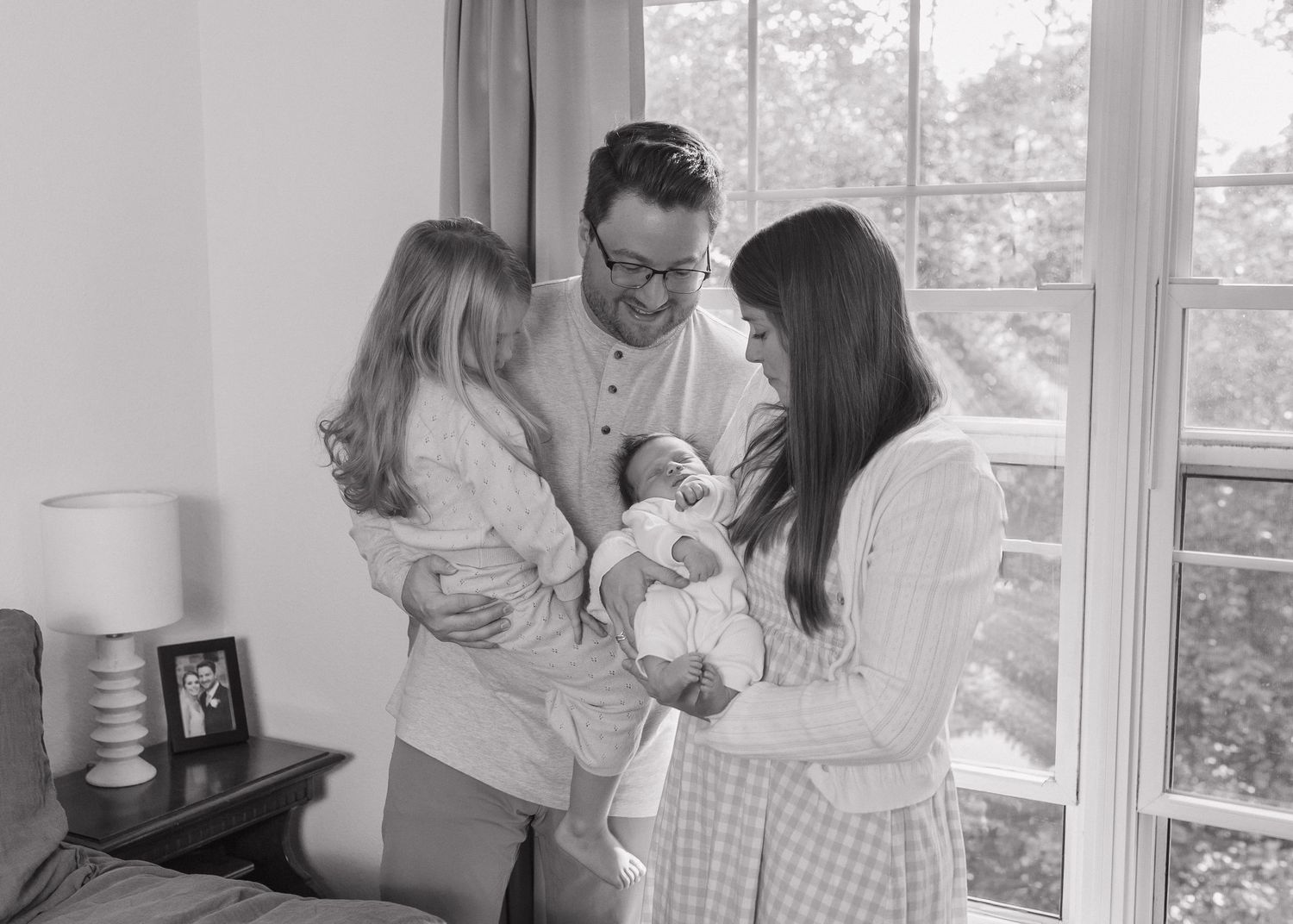 A series of black and white photos showing tender family moments and interactions in a bright interior setting.