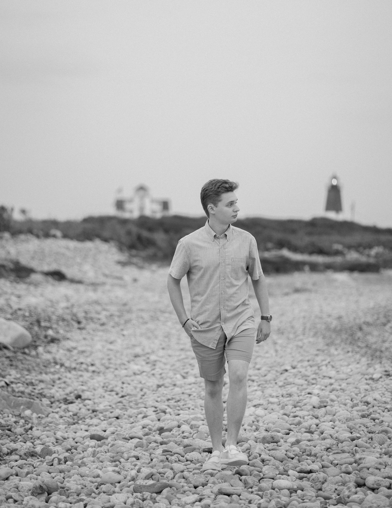Black and white coastal scene with a lighthouse silhouette in the distance.