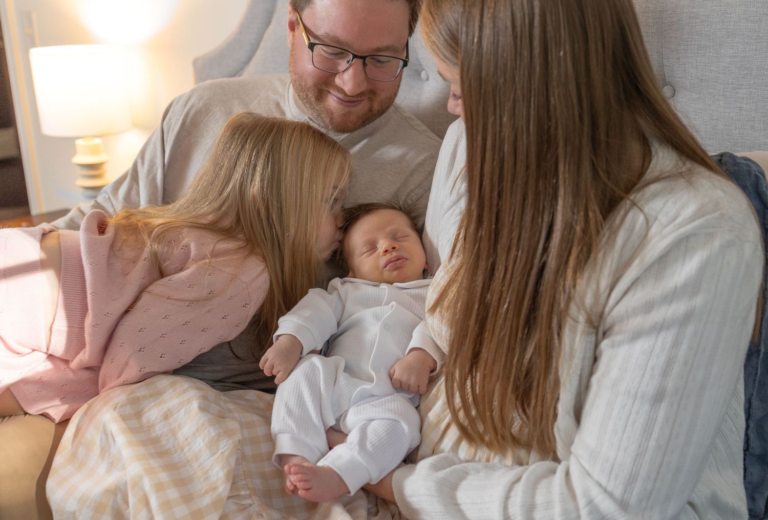 Close-up lifestyle photos capturing gentle interactions between parents and their infant in a bedroom setting.