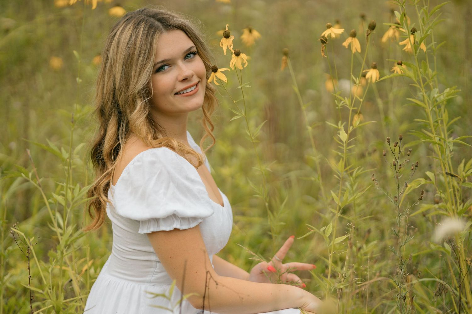 A summer portrait in a wildflower meadow featuring a white dress against yellow blooms.
