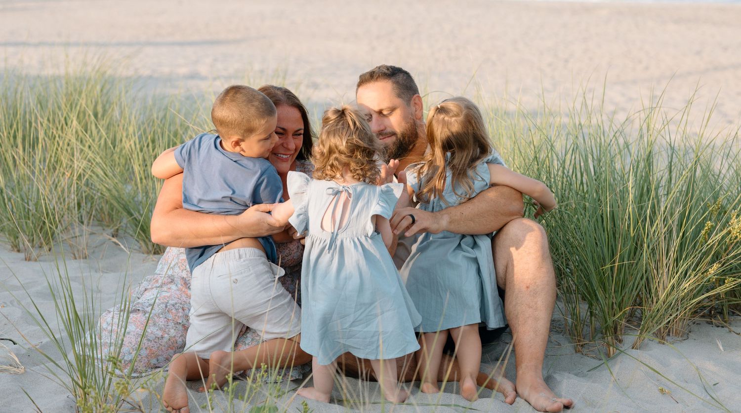 Intimate family gathering on beach dunes at sunset with sea grass in background.