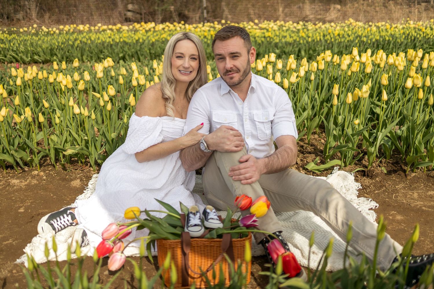 Couple having a spring picnic among blooming yellow tulips in a garden.