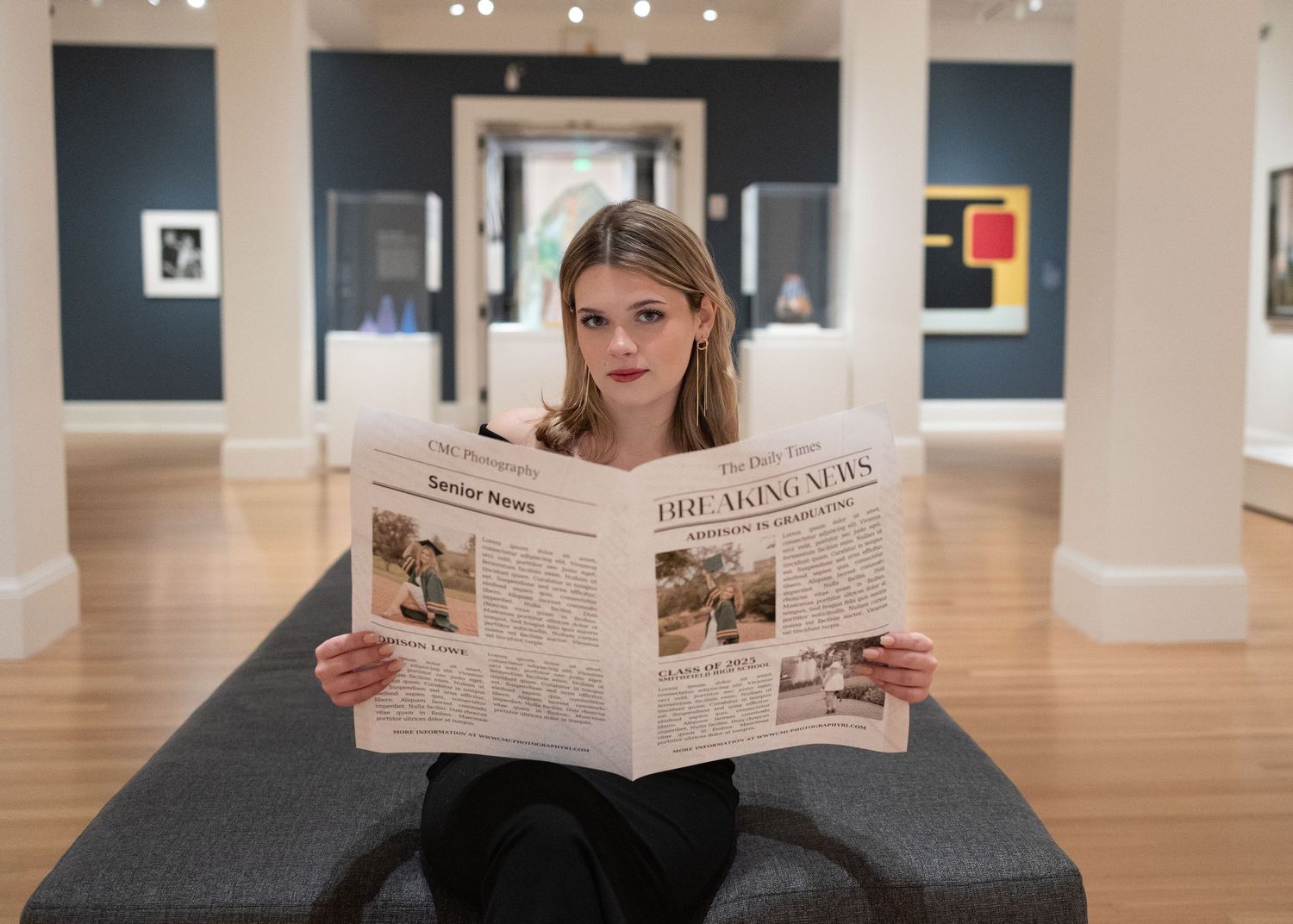 Person reading a newspaper while lounging in an art gallery with framed artwork displayed on walls.
