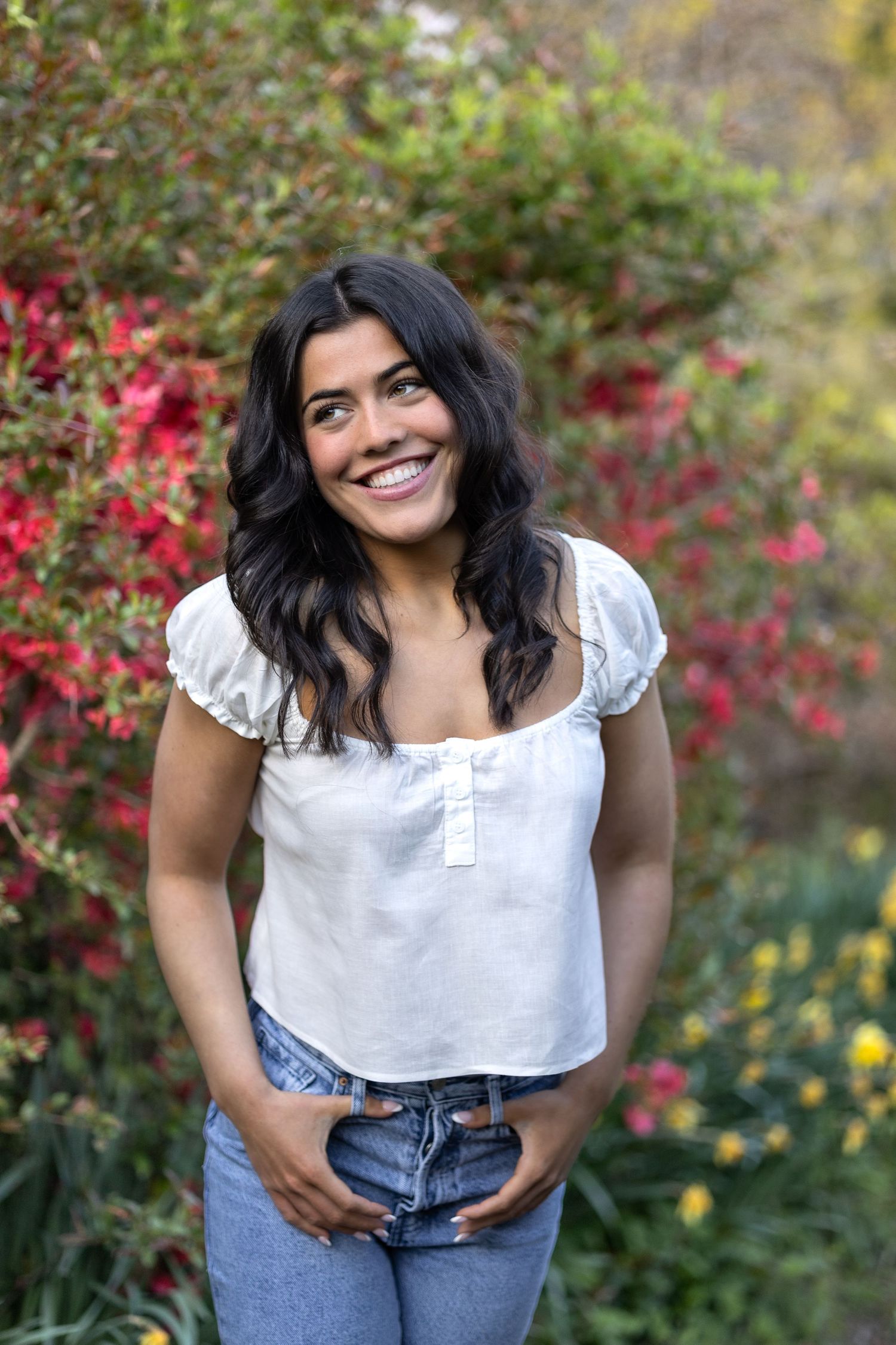 Rhode Island senior girl in white top and jeans laughing  in azalea garden with vibrant red and green foliage