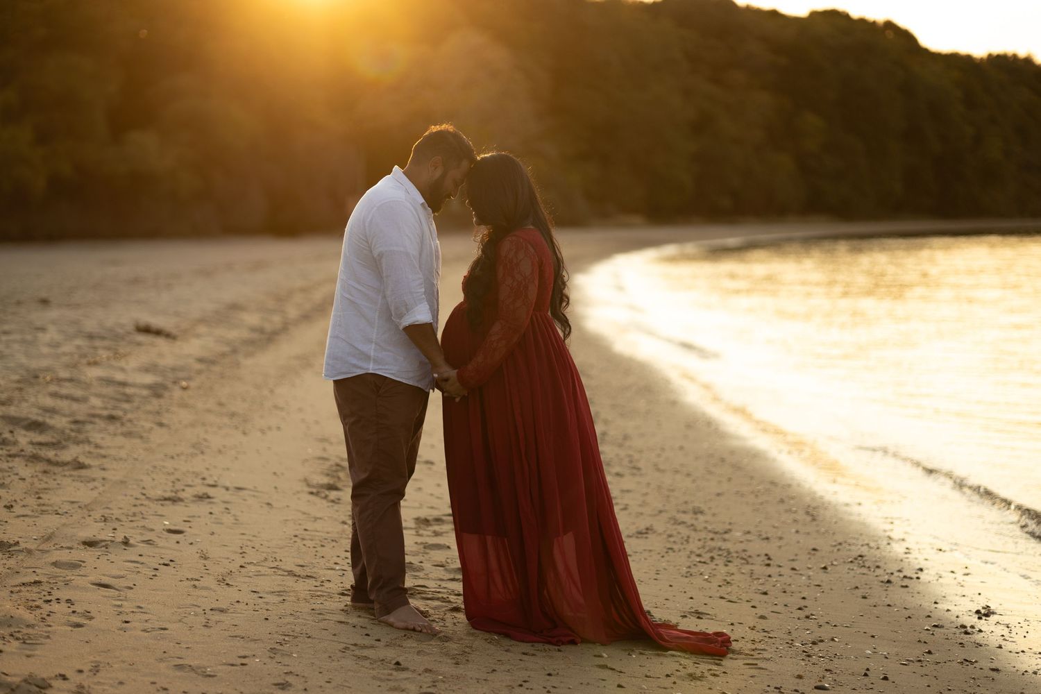 Romantic silhouette of couple on beach at sunset with flowing red dress.