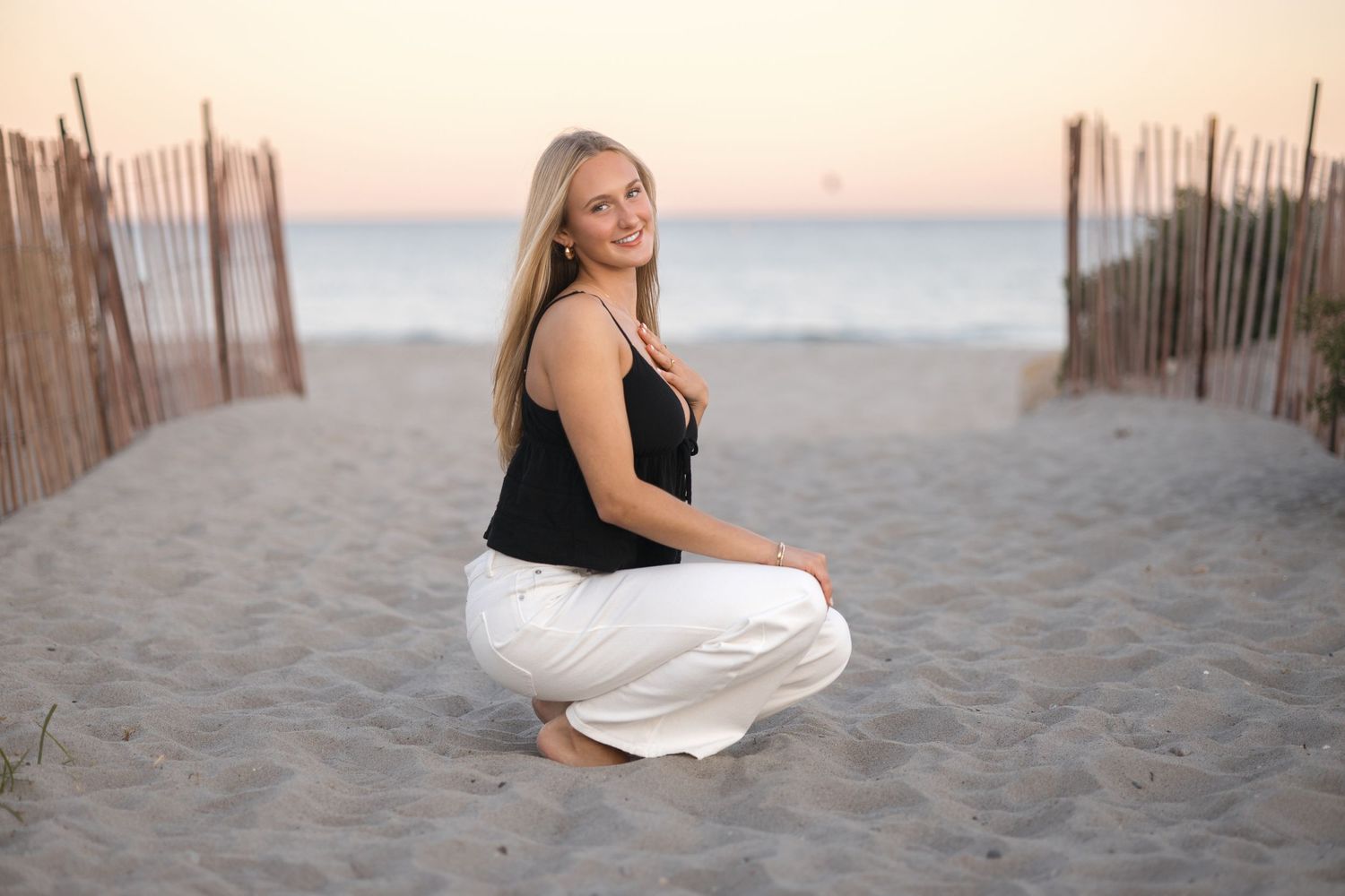 Beach portrait between wooden fence posts at sunset.