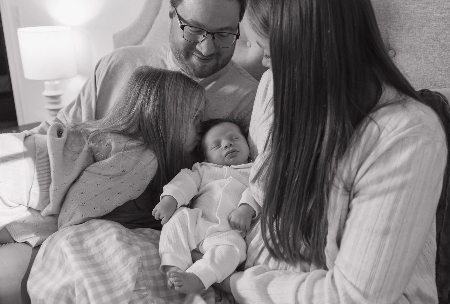 A series of black and white photos showing tender moments between parents and their newborn baby in a hospital setting.