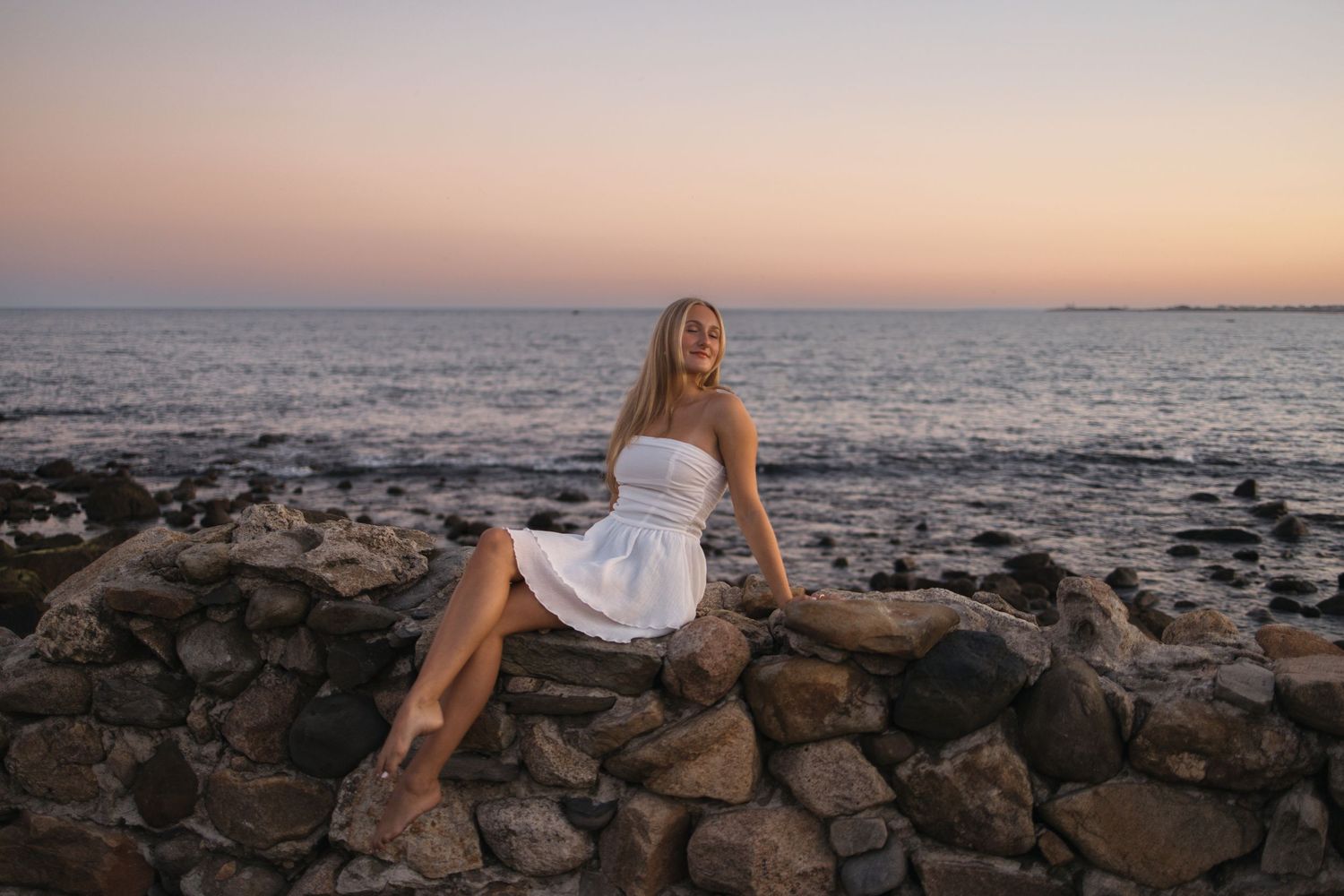 A sunset beach portrait with rocky coastline and ocean views in the background.