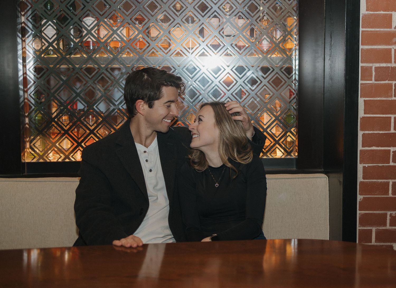 A romantic moment shared in a restaurant booth with decorative wall lighting.