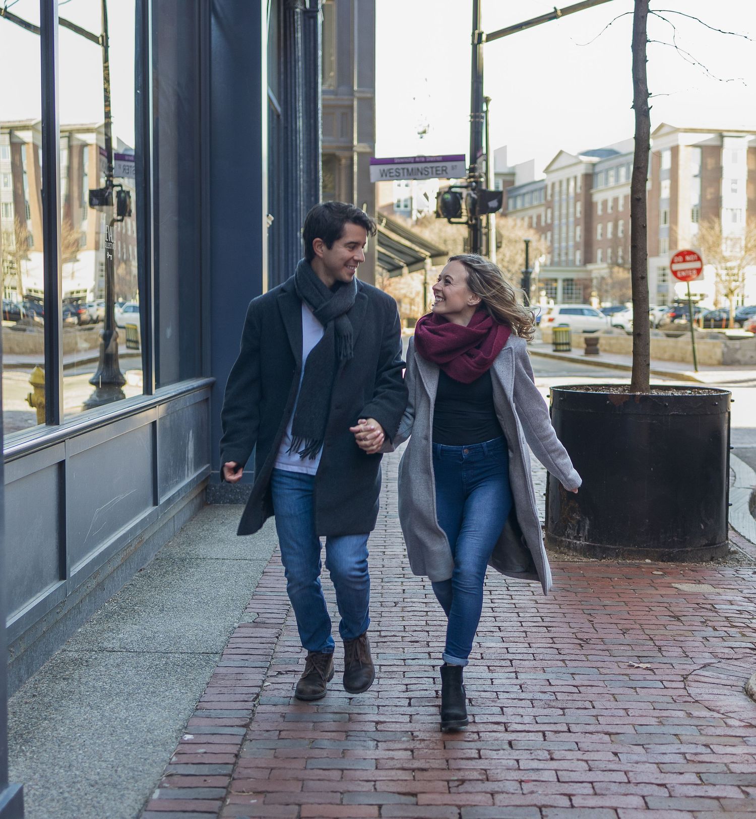 A couple taking a romantic stroll along a city sidewalk.