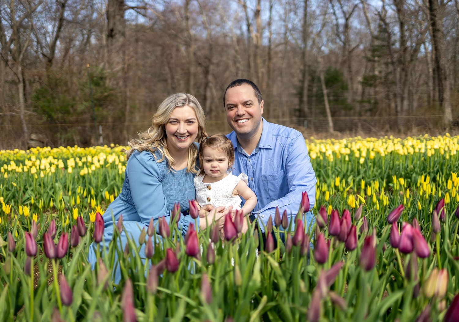 Family portrait surrounded by blooming spring tulips and daffodils.