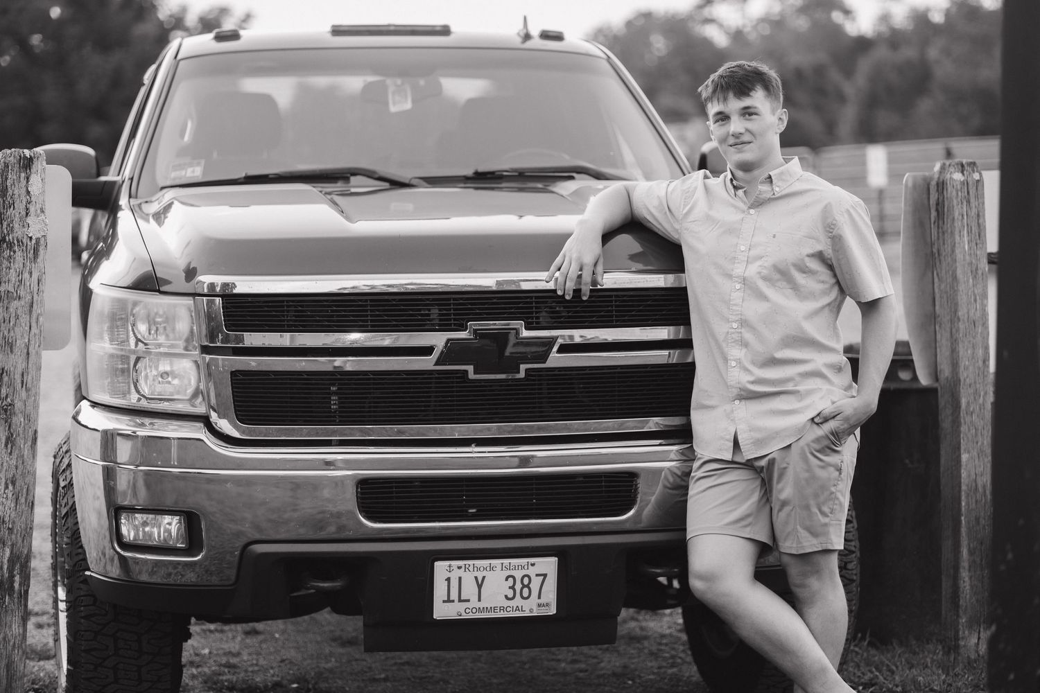 Person leaning against black Chevrolet pickup truck in casual attire.