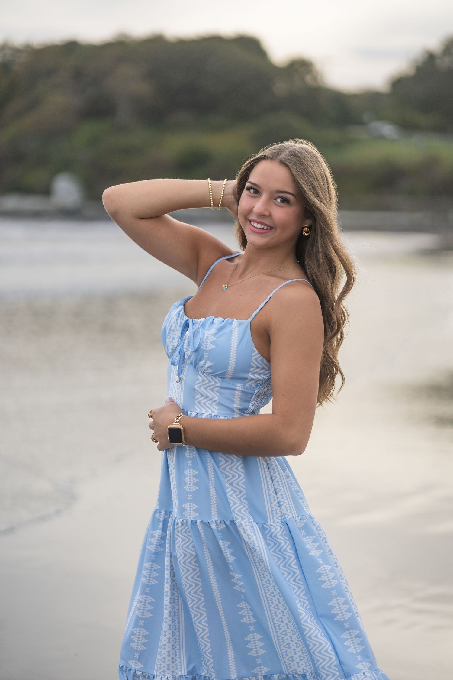 A light blue patterned sundress creates a summery silhouette against a waterfront backdrop at sunset.