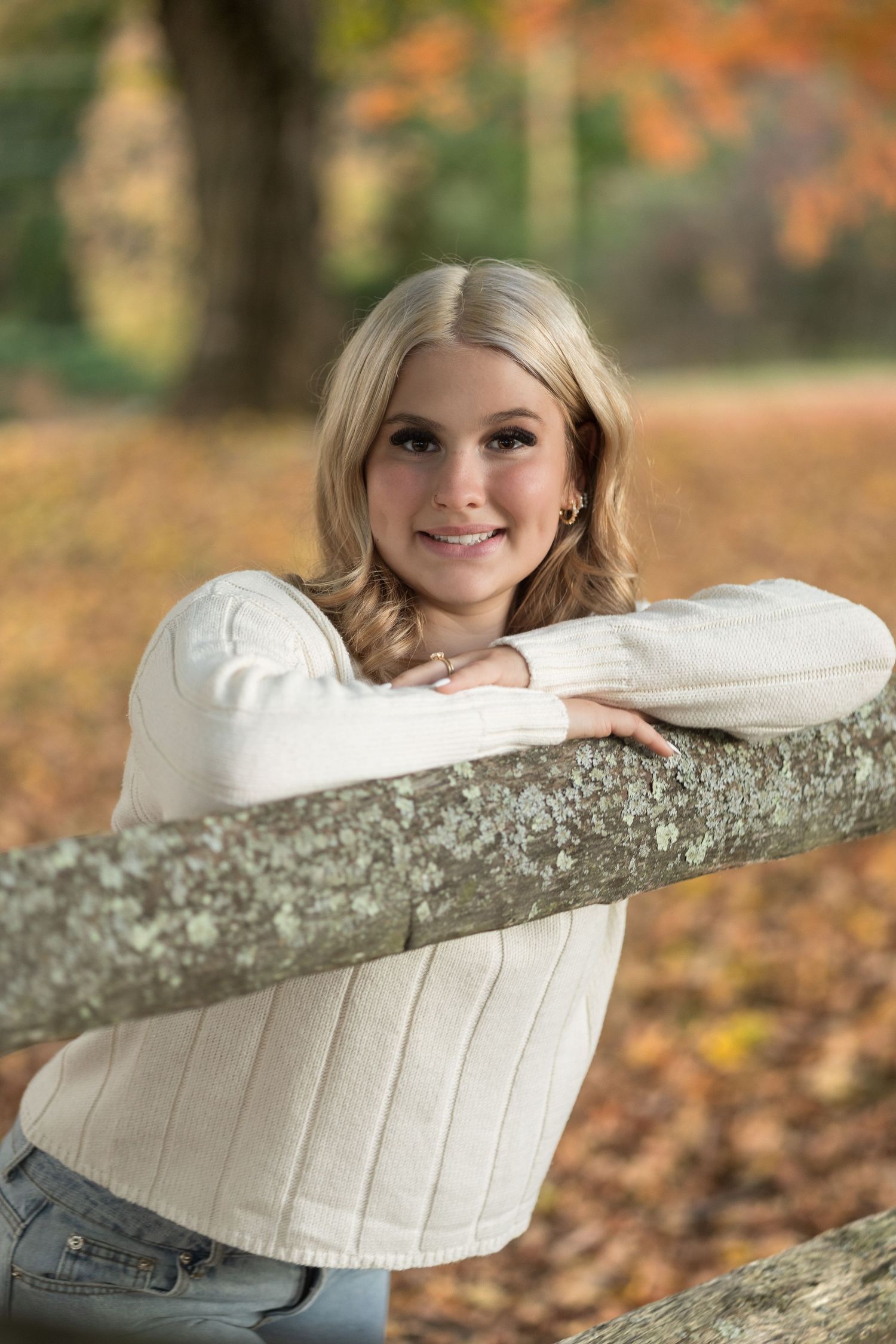 A series of autumn portraits showing someone in a white sweater leaning on a log surrounded by fallen leaves.