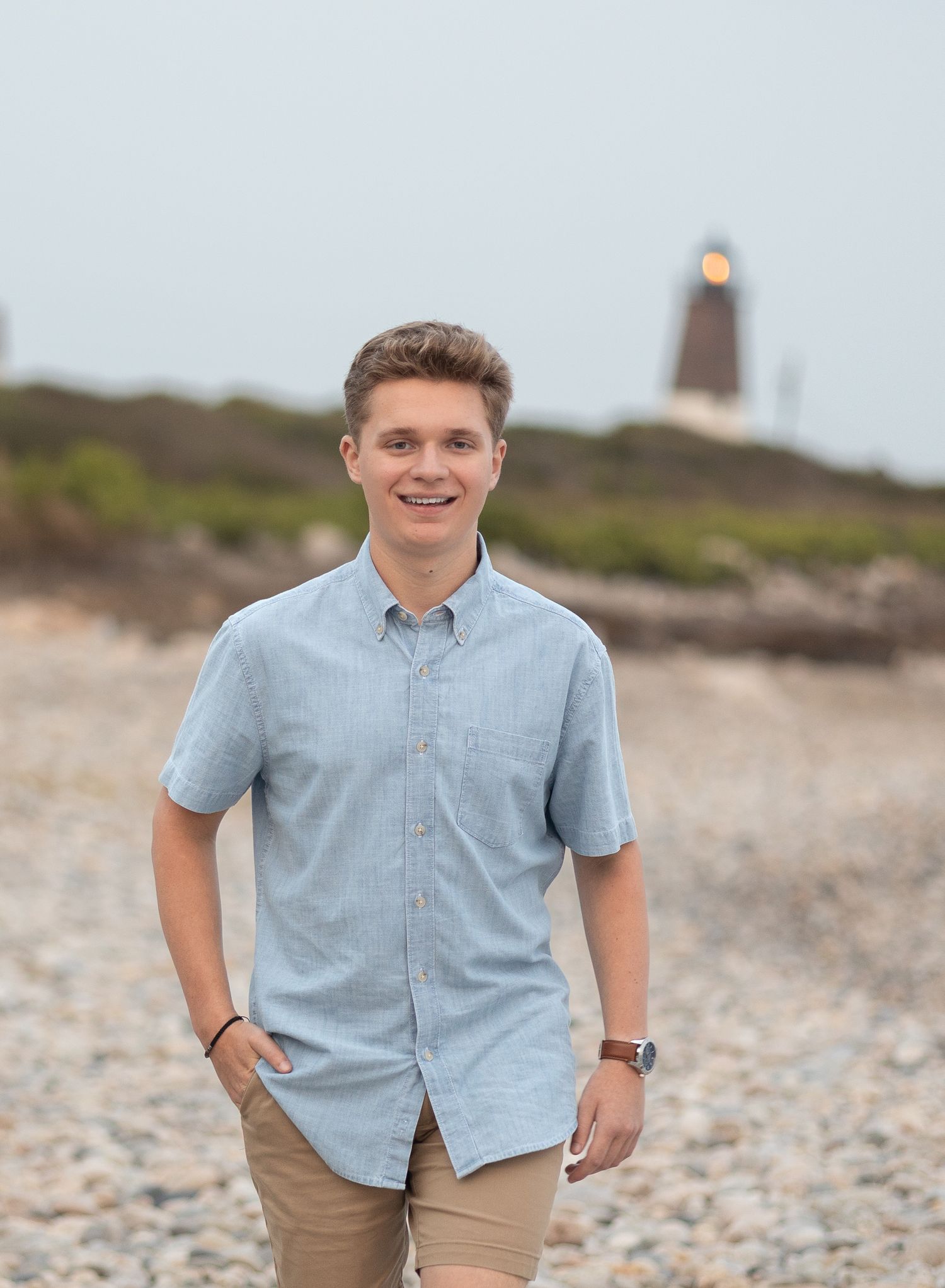 Casual outdoor portrait with a lighthouse visible on the hill behind.