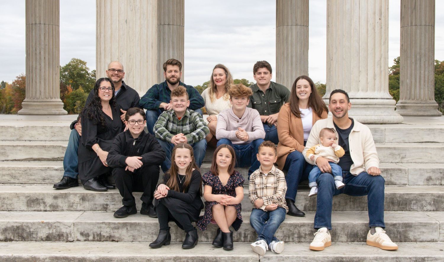 Extended family poses together on stone steps with white columns in the background.