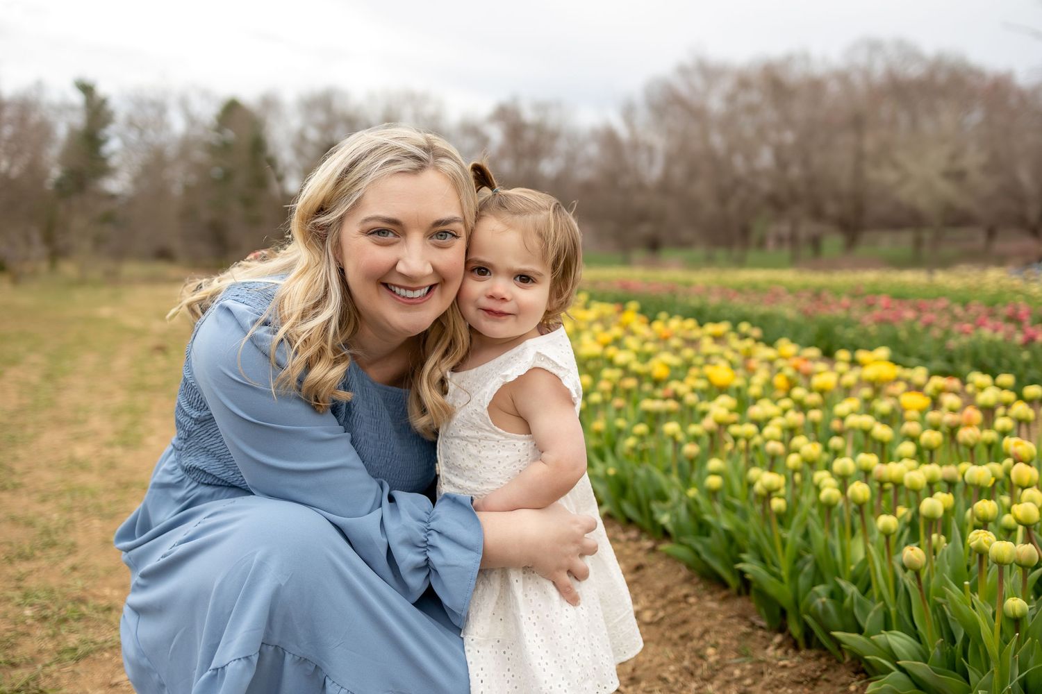 Spring portrait amidst rows of colorful tulips and daffodils.