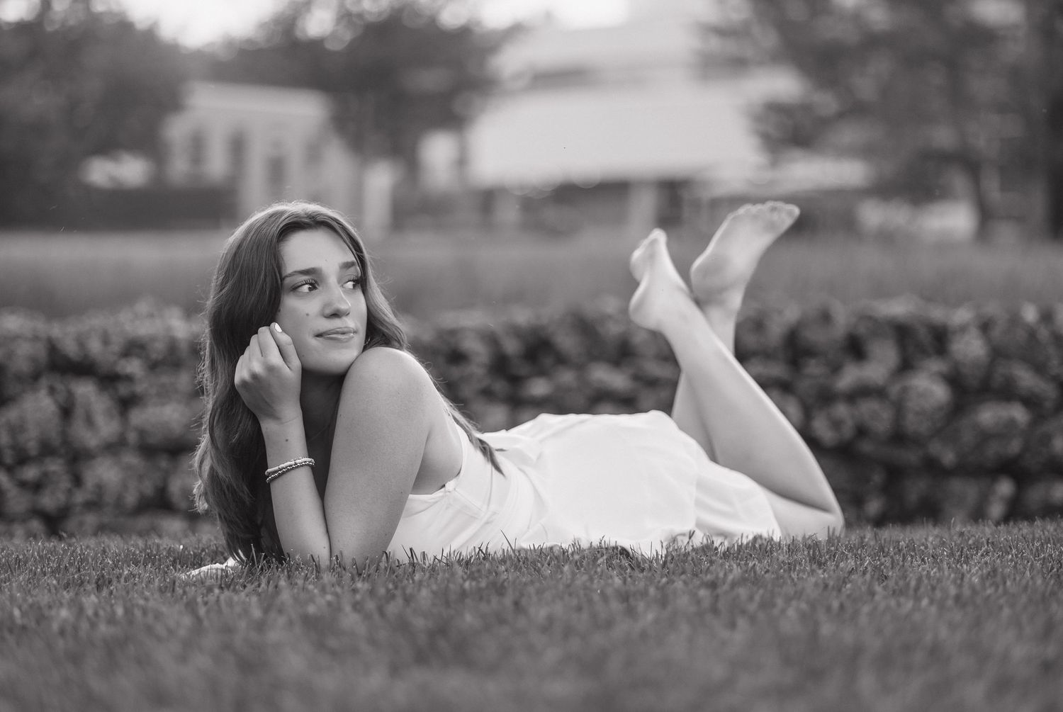 Black and white artistic portrait series showing someone lying in grass with dreamy, contemplative poses.