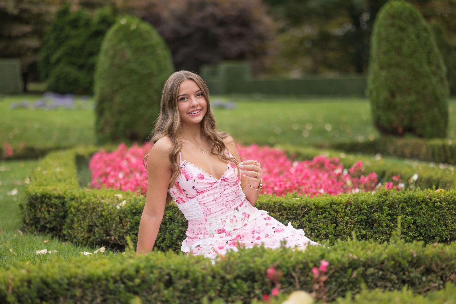 Outdoor photo series in a manicured garden with pink flowers and hedges.