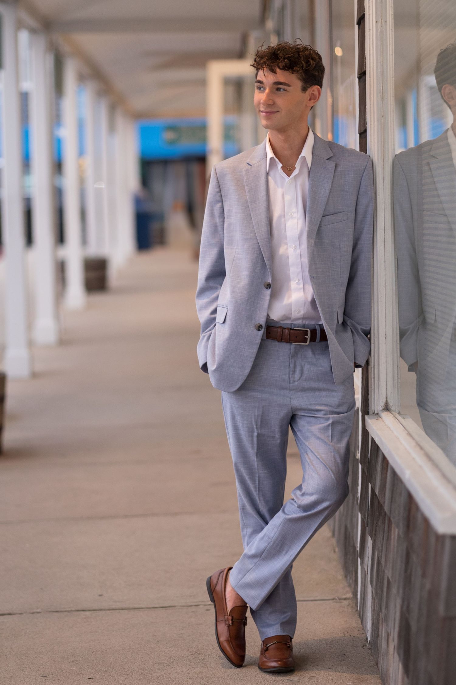 Professional fashion shot showing light blue suit and white shirt in covered walkway.