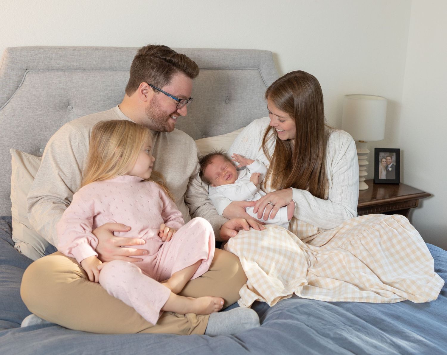 A series of intimate lifestyle photos showing tender moments between parents and their newborn baby on a bed.