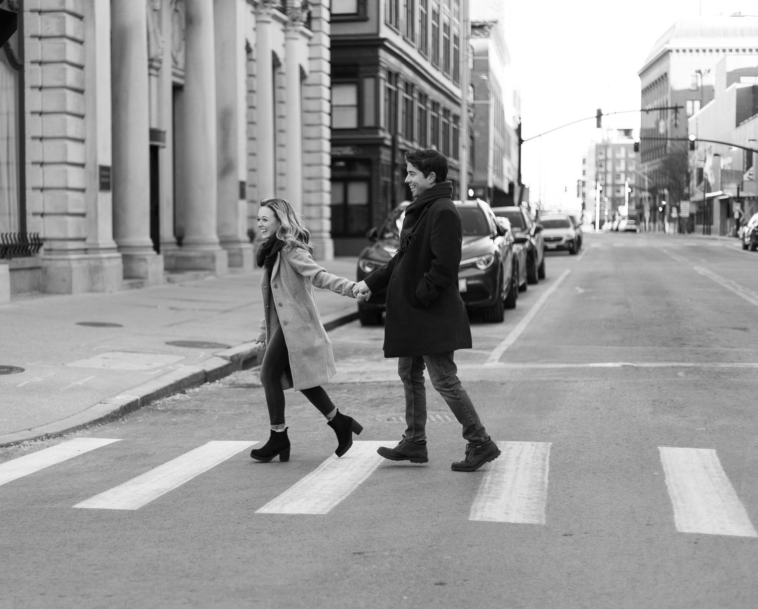 A playful black and white photo of a couple crossing a city street.