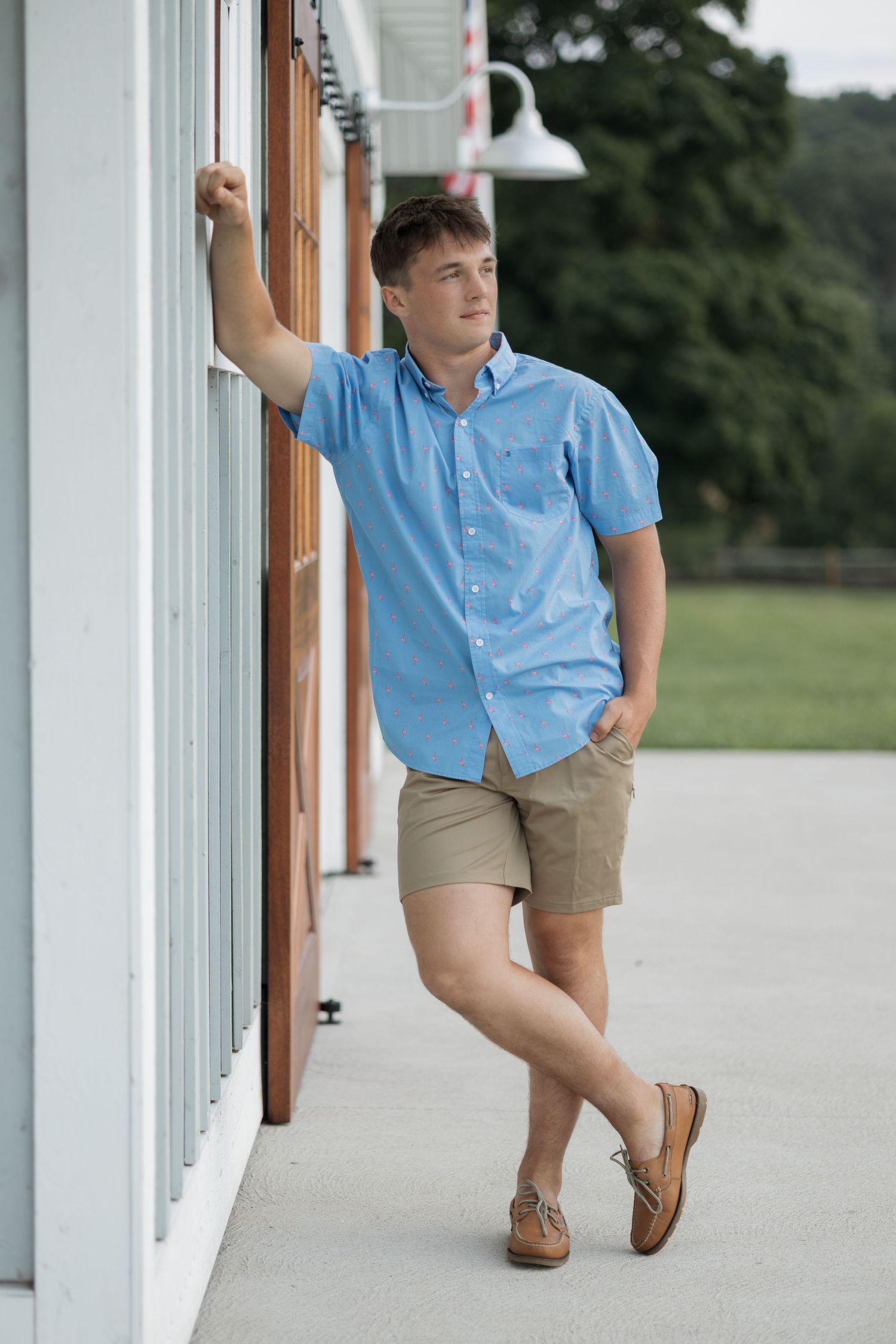 Casual summer outfit with blue shirt and khakis while posing against white wall outdoors.