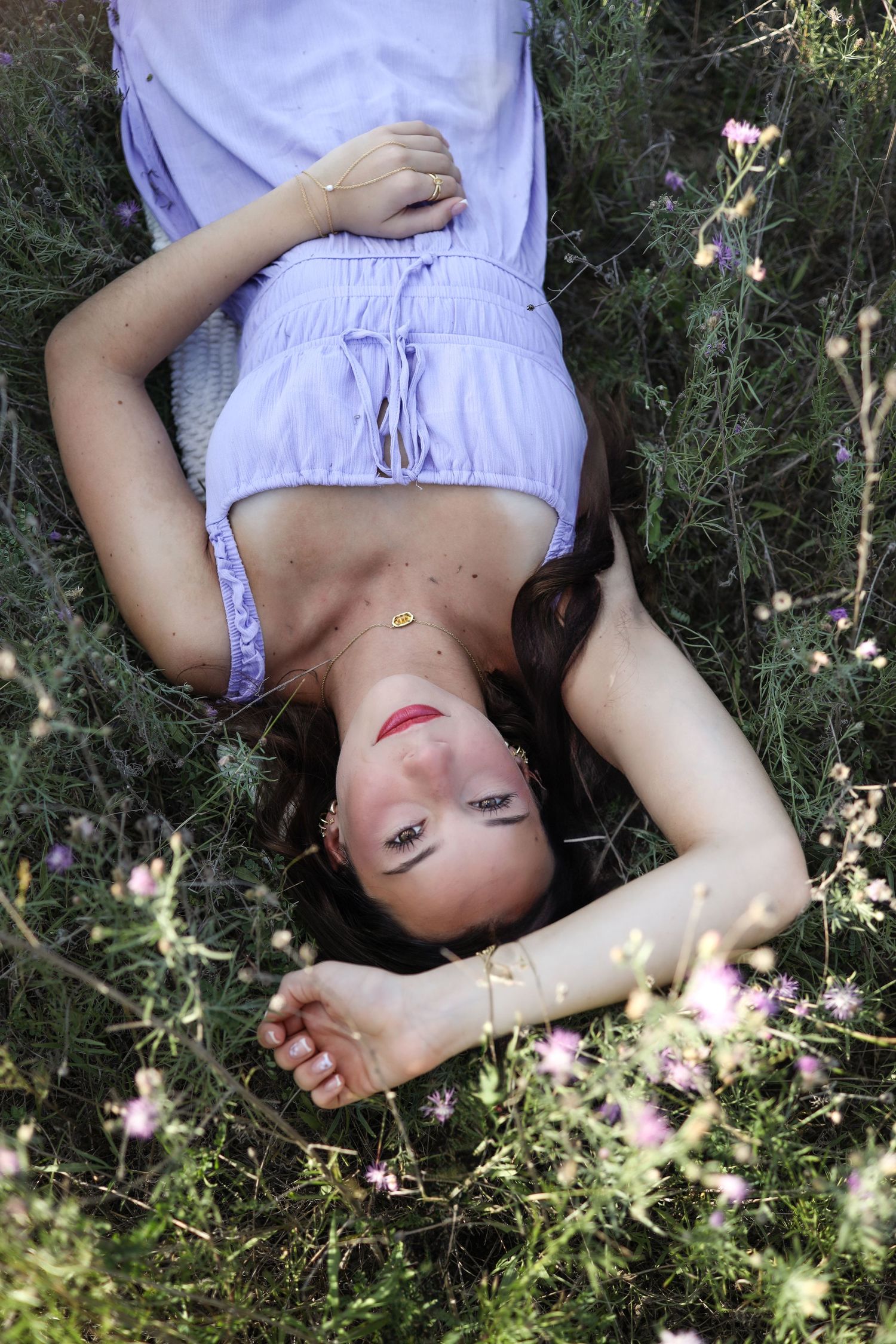 Artistic portrait series showing someone lying in grass with dappled sunlight and delicate flowers.