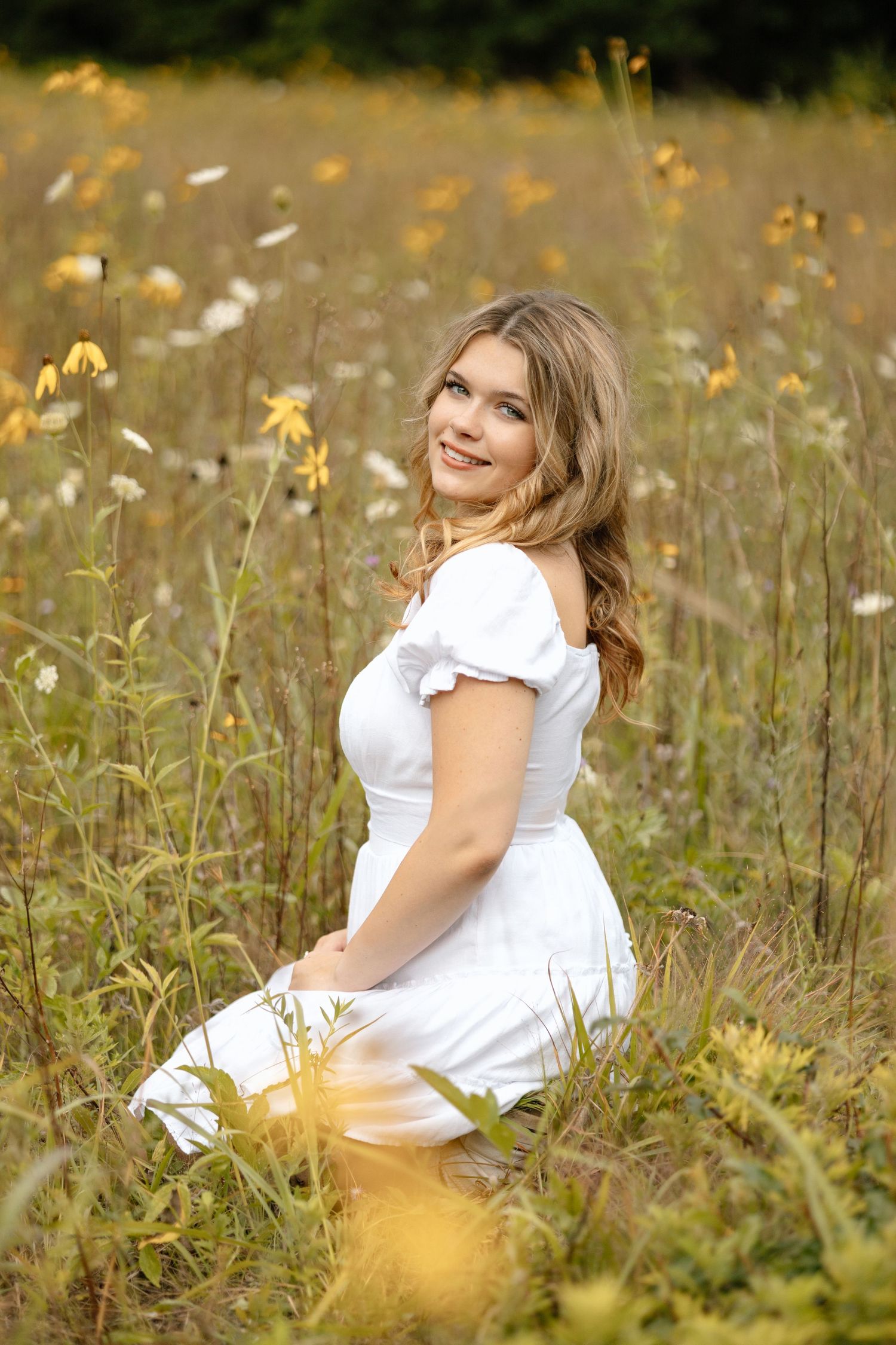 A dreamy summer portrait in a meadow with white dress among yellow wildflowers.