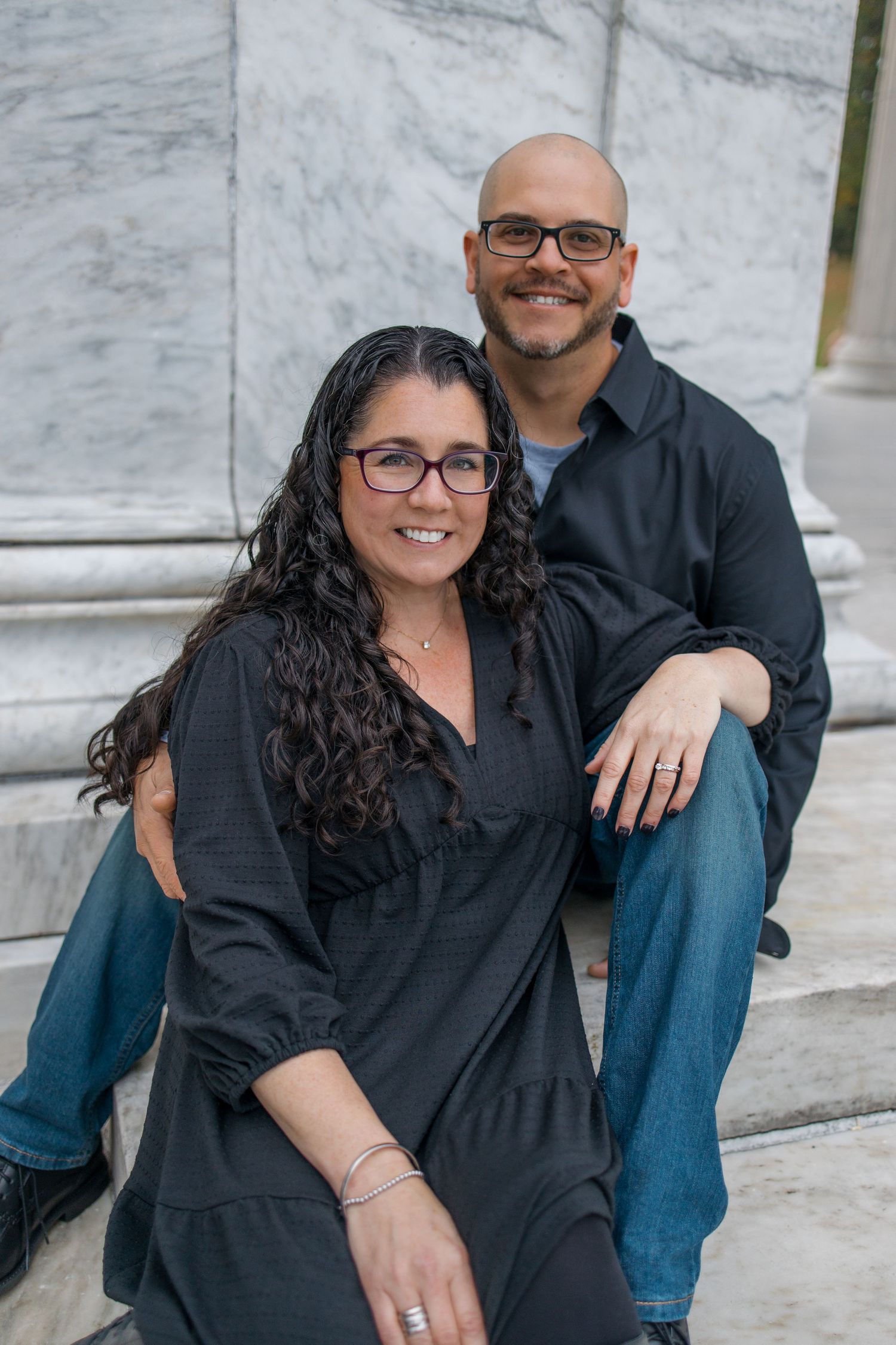 A couple sits together on marble steps showing affection.