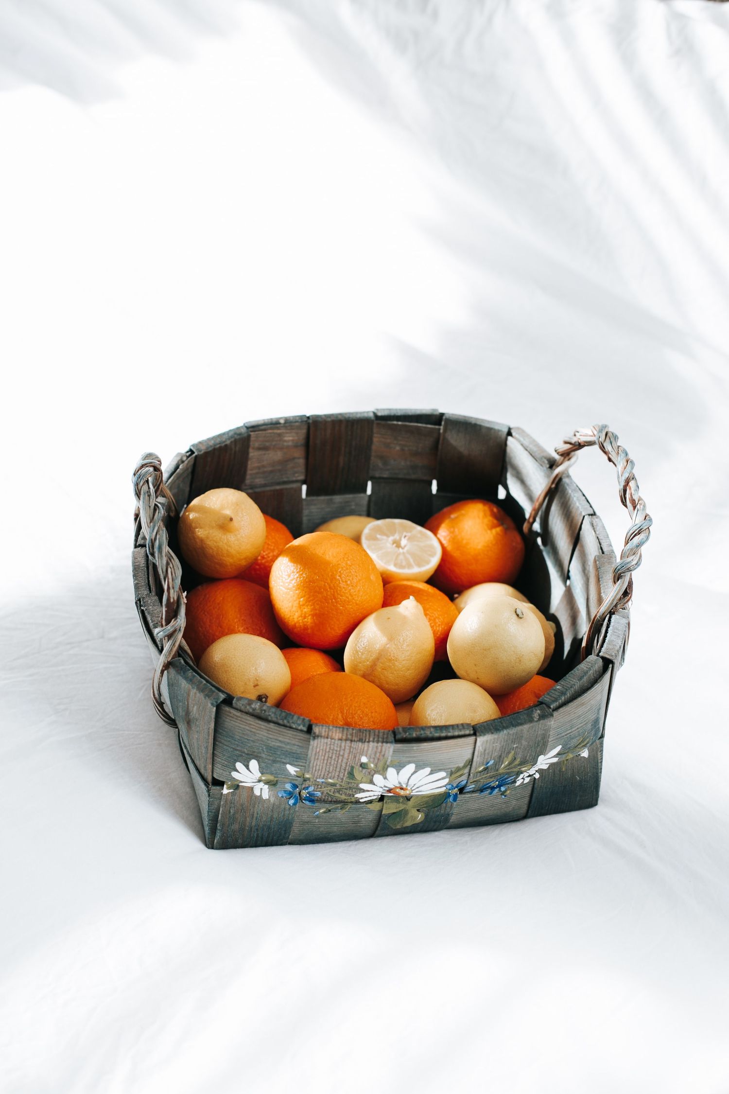 Fresh citrus fruits displayed in a decorative metal basket on white background.