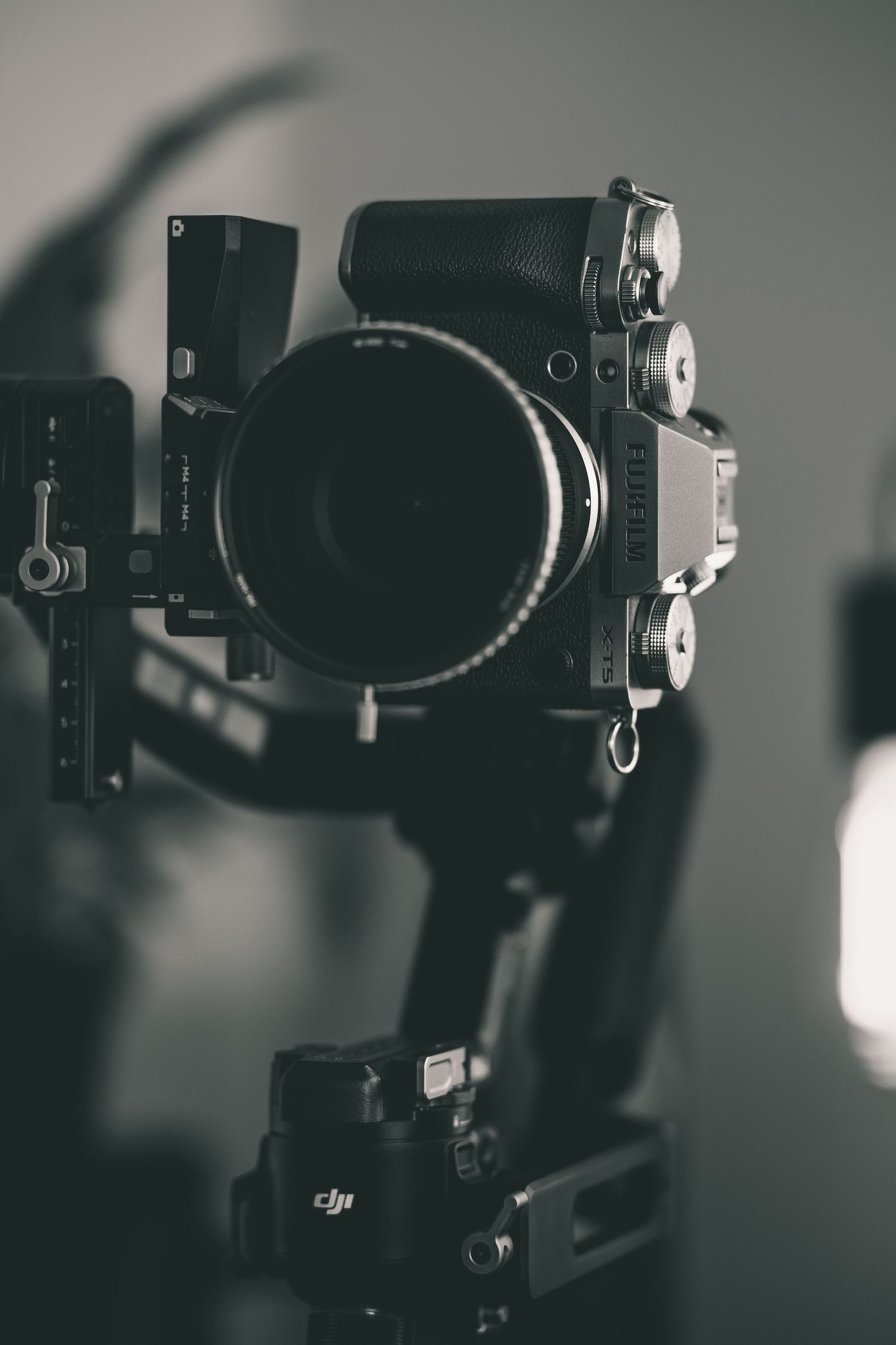 Black and white photo of a professional camera mounted on a DJI gimbal stabilizer with a large lens.