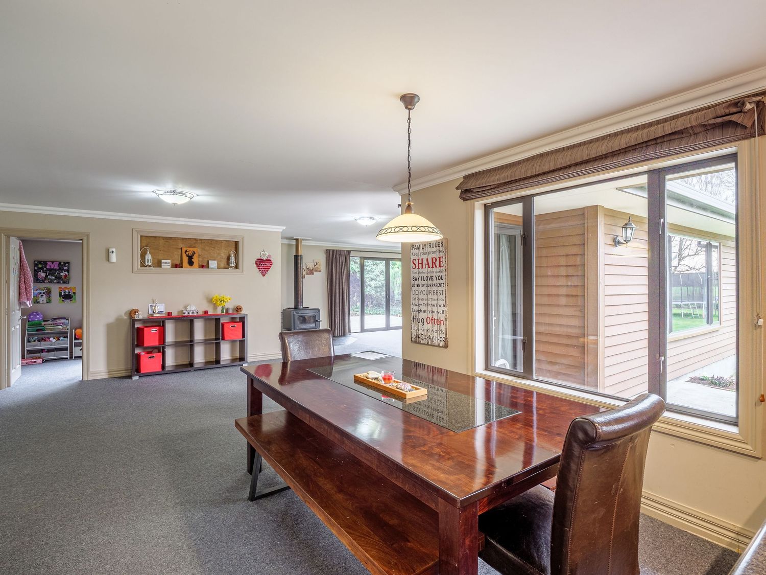 Spacious open concept living area with hardwood floors, large windows, and modern lighting fixtures in a residential home.