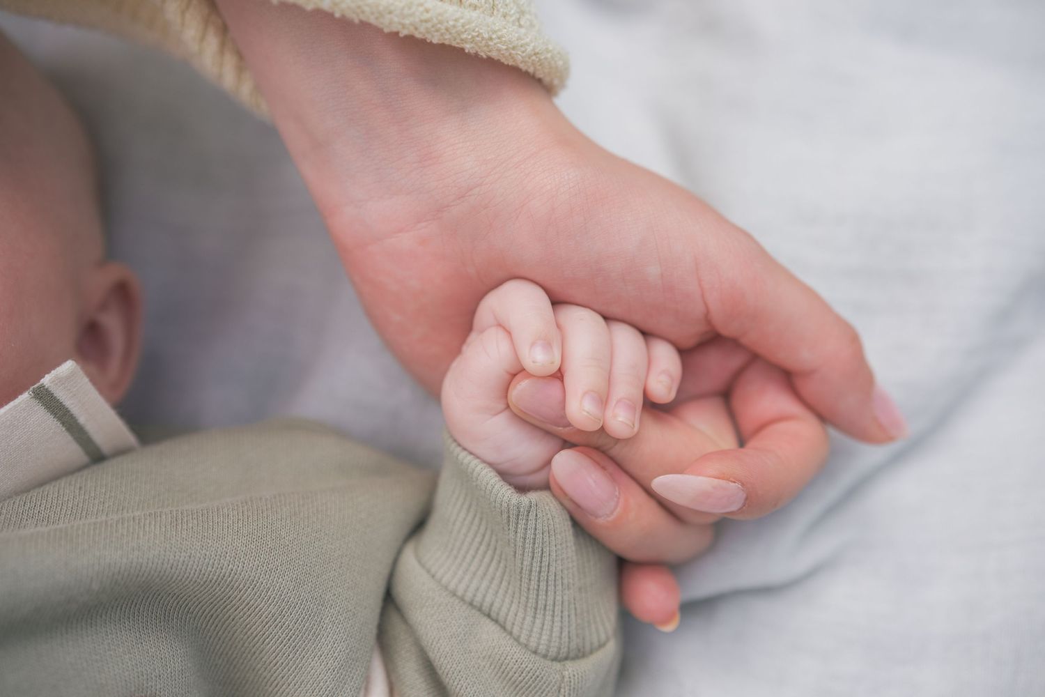 Close-up shots of tiny baby feet and hands wearing a soft gray outfit.