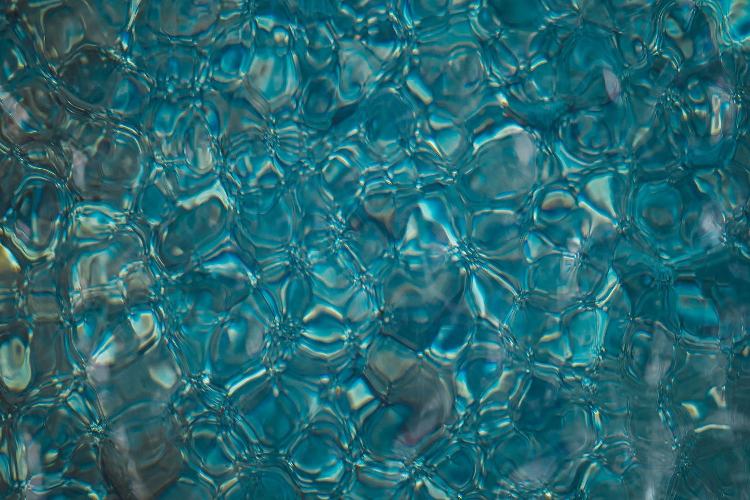 Abstract background pattern of translucent blue glass or crystal shapes creating a kaleidoscopic texture.
