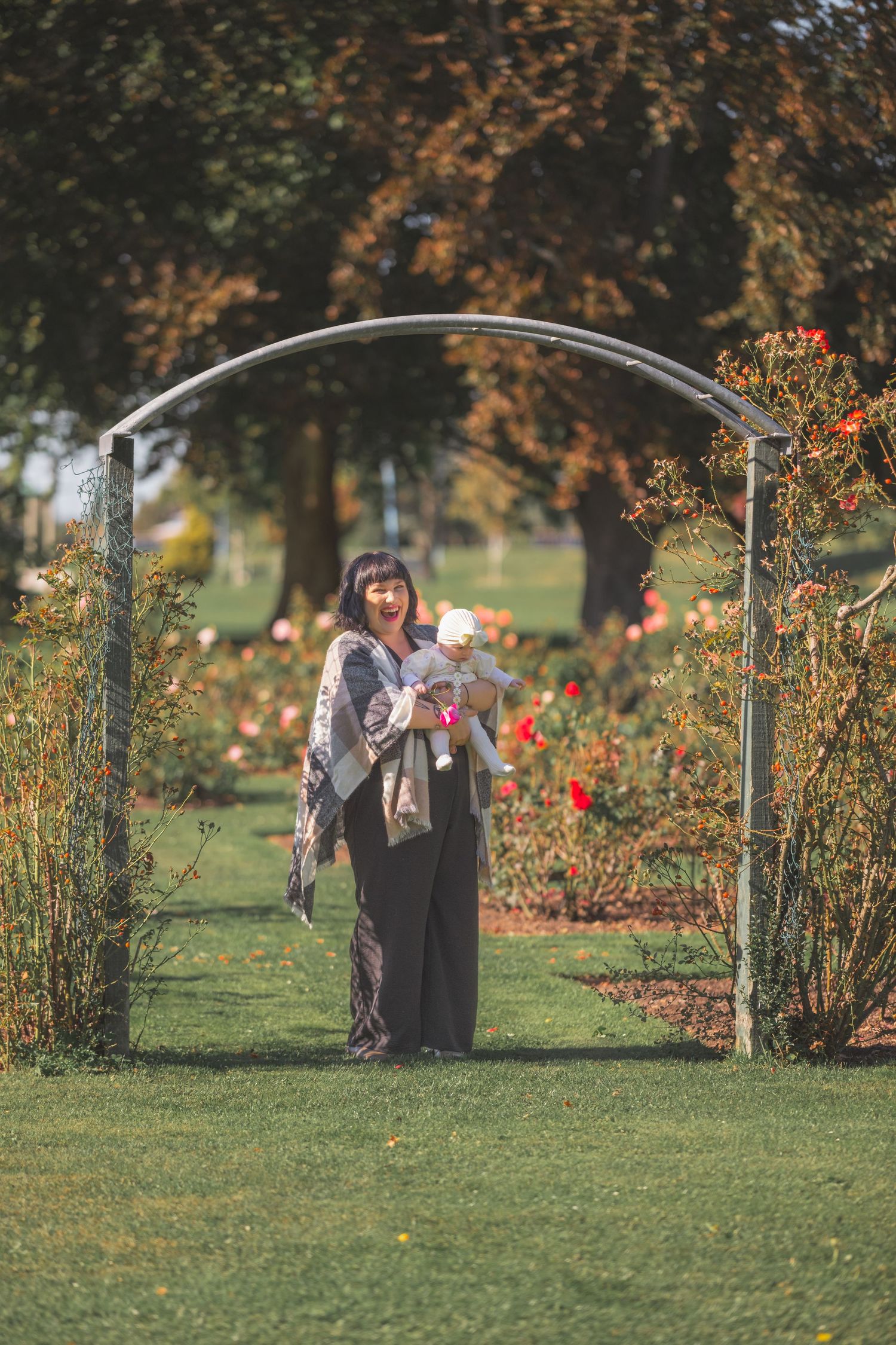 People enjoying a stroll through a blooming autumn garden with red flowers and golden foliage.