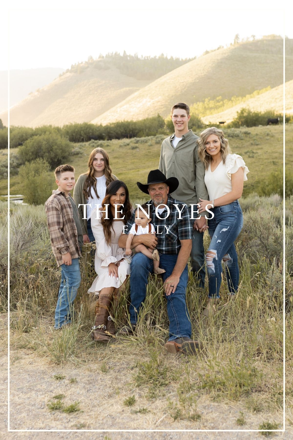 A casual family photo in the countryside with rolling hills in the background at sunset.