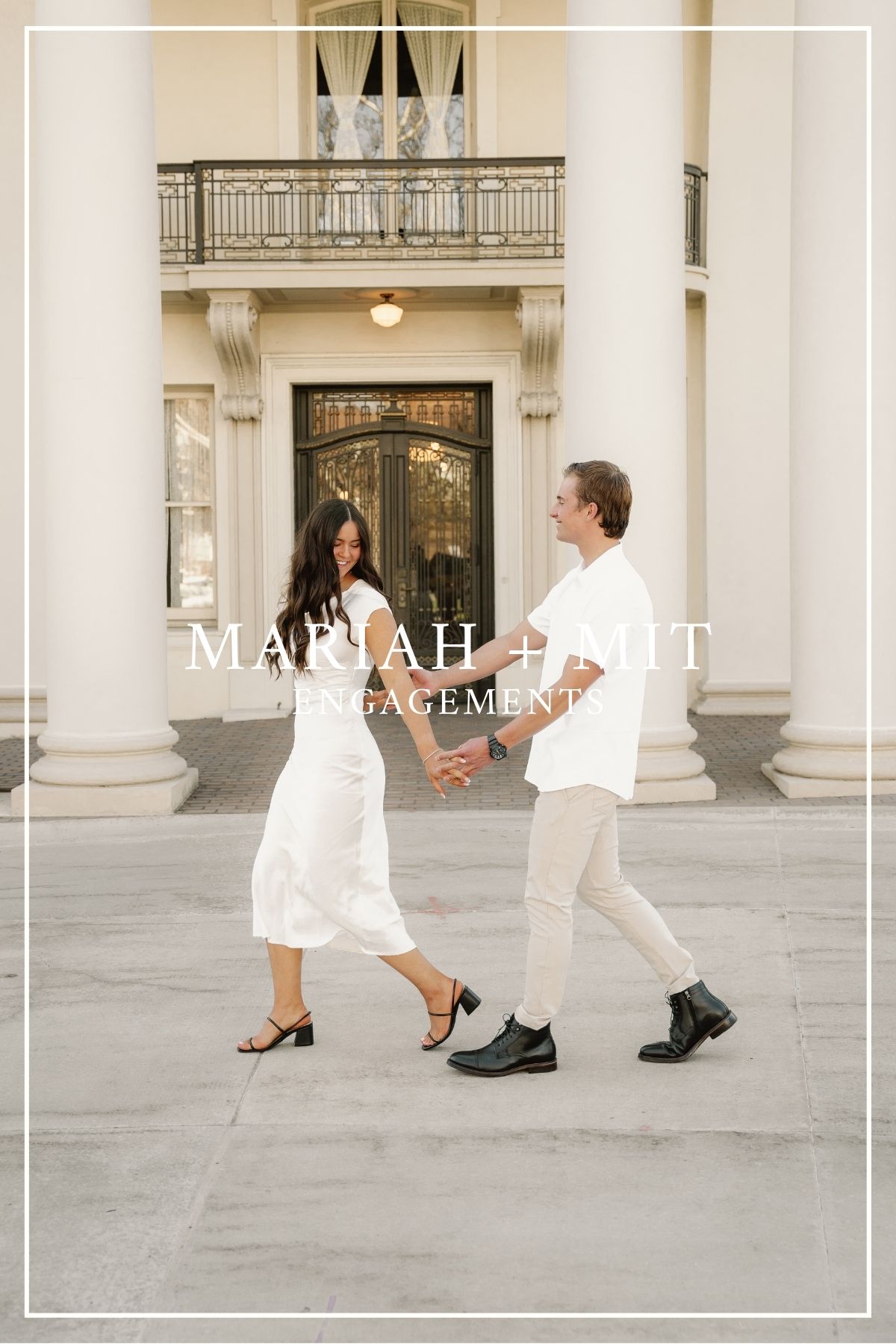 A couple in matching white outfits dance playfully on a porch with elegant columns and ornate doorway.