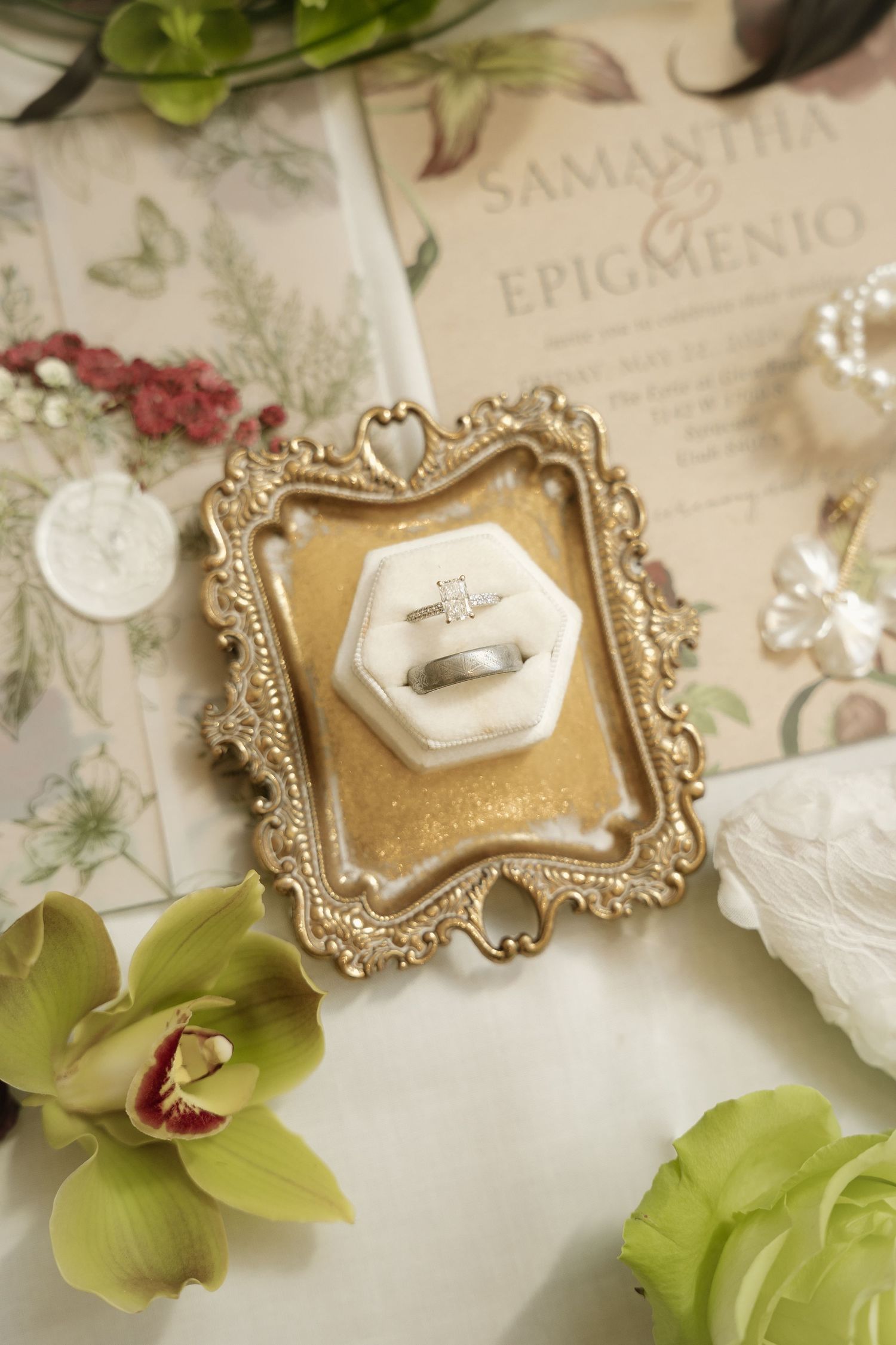 Elegant wedding rings displayed in a vintage gold frame with wedding invitation for Samantha and Epigmenio.