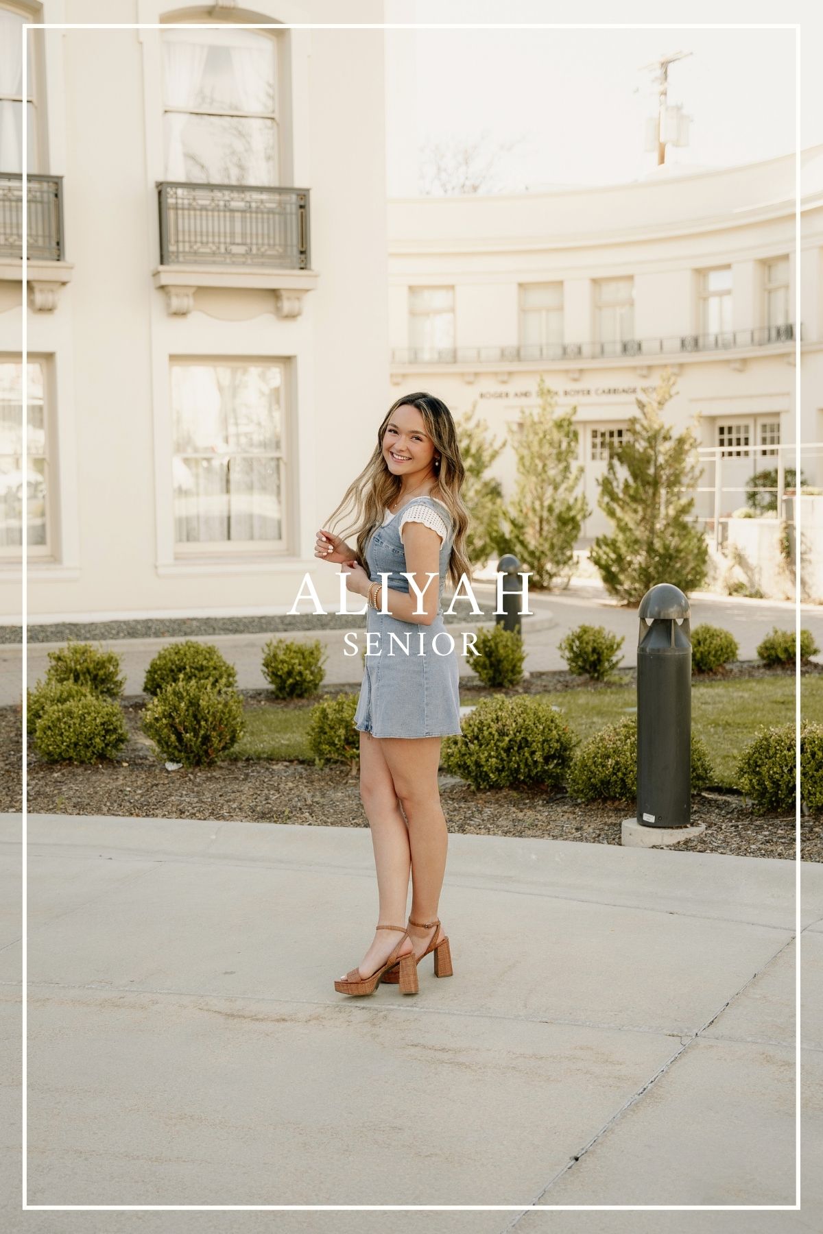 A summer senior portrait session with someone in a light blue dress standing outside an elegant white building.
